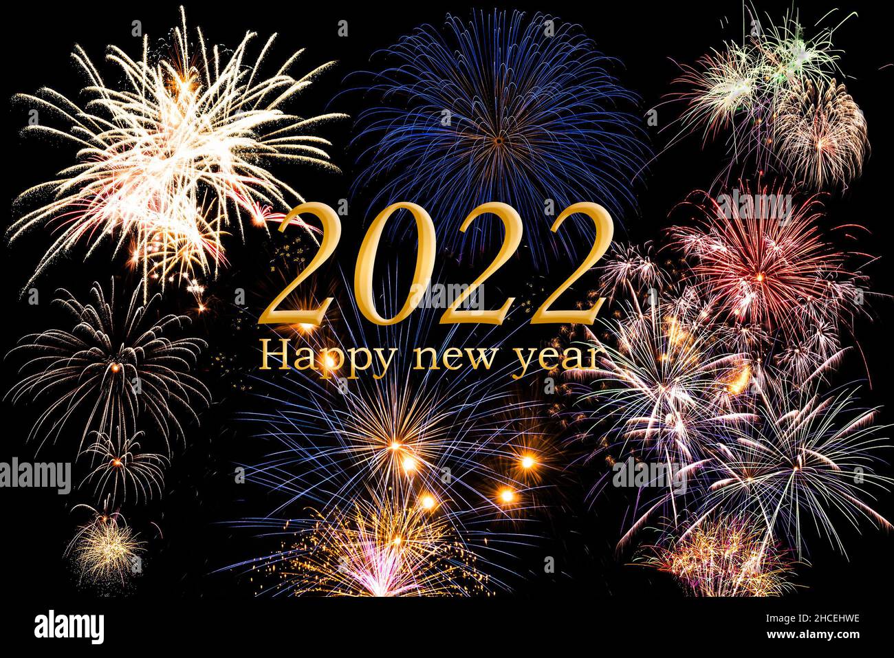 Frohes neues Jahr 2022. Text und Numer in goldener Farbe mit hellem Feuerwerk und dunklem Himmel im Hintergrund. Stockfoto