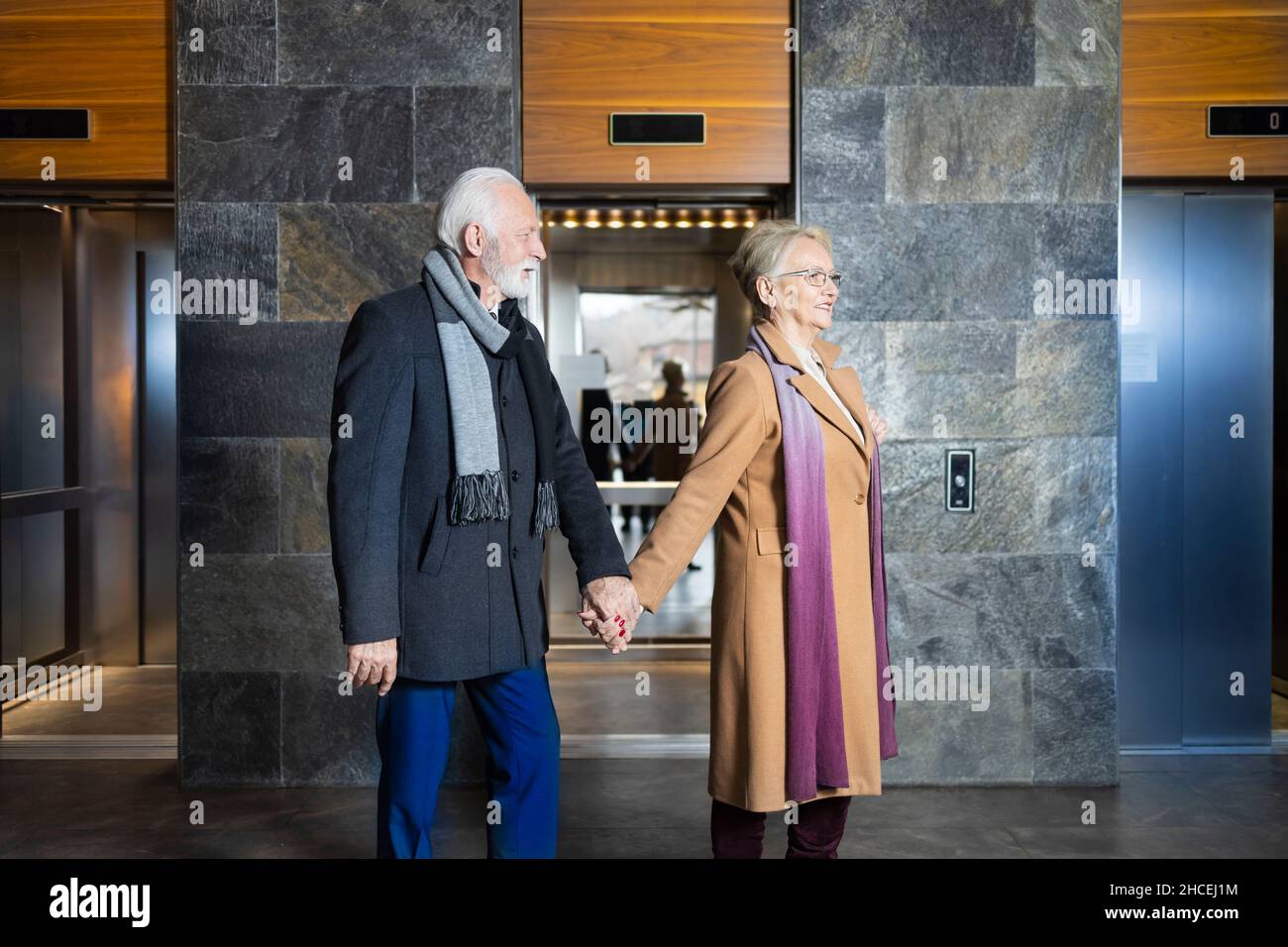 Ältere Frau und Ehemann halten sich im Hotel die Hände Stockfoto