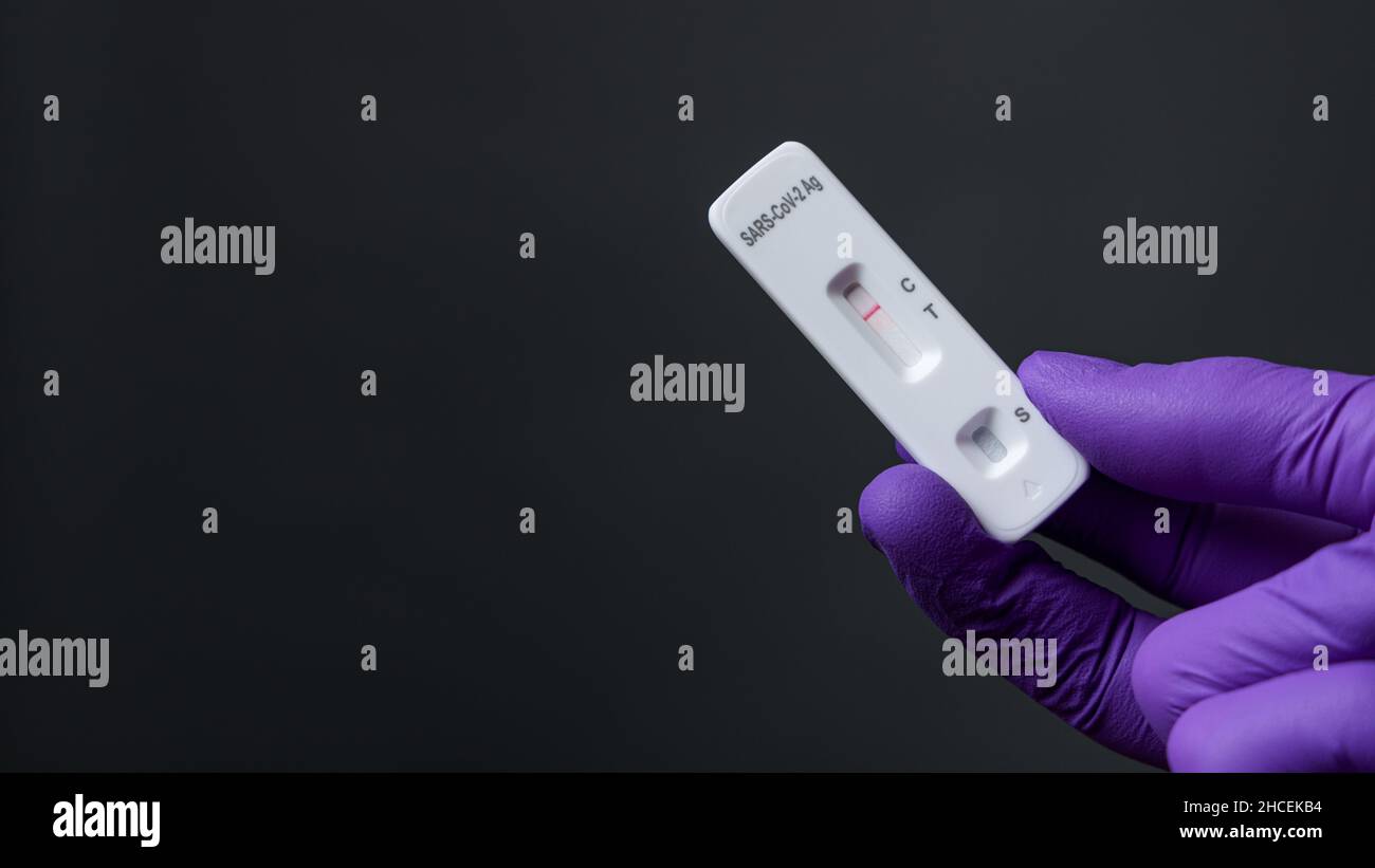 Hand mit Handschuh, der einen negativen Antigenschnelltest hält Stockfoto