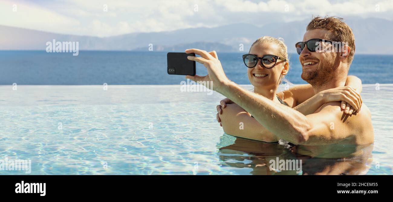 Sommerurlaub - junges glückliches Paar, das Selfie mit dem Telefon im Resort-Schwimmbad macht. Banner-Kopierraum Stockfoto