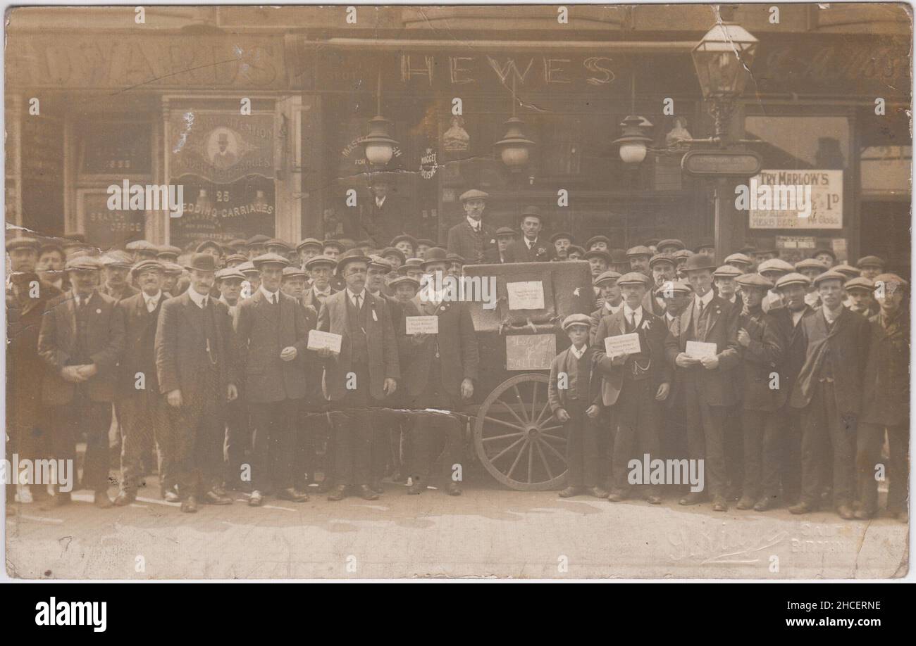 1913 Schwarzlandstreik: Im Mai 1913 reiste eine Prozession von Streikenden aus Handsworth & Oldbury nach Saltley, um Unterstützung von lokalen Wagenarbeitern zu erhalten. Dieses Foto zeigt eine große Gruppe von Männern, die auf der Straße demonstrierten. Zwei Männer stehen auf einem Wagen, auf dem „Onkel Joe von Saltley“ steht. Einige Männer halten Sammelkisten mit dem Aufschrift „Eisenbahnwaggons- und Wagenarbeiterstreik-Fonds“ in der Hand. Zu den Geschäften im Hintergrund gehören Hewes und Edwards. An der Straßenlaterne ist ein Schild mit der Aufschrift „Stephenson Place“ zu sehen. Die Fotopostkarte wurde von Ridge of Saltley verkauft Stockfoto