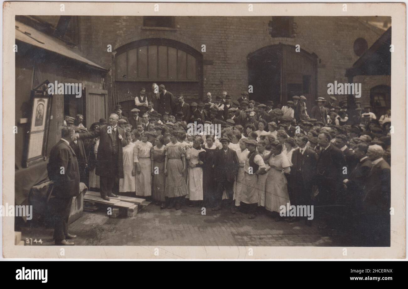 Foto des Arbeitshaustreffens im frühen 20. Jahrhundert: Mann auf erhöhter Plattform, der sich an eine Menschenmenge wendet, einschließlich Frauen in Schichten, die als Arbeitshauskleidung ausgestellt wurden Stockfoto