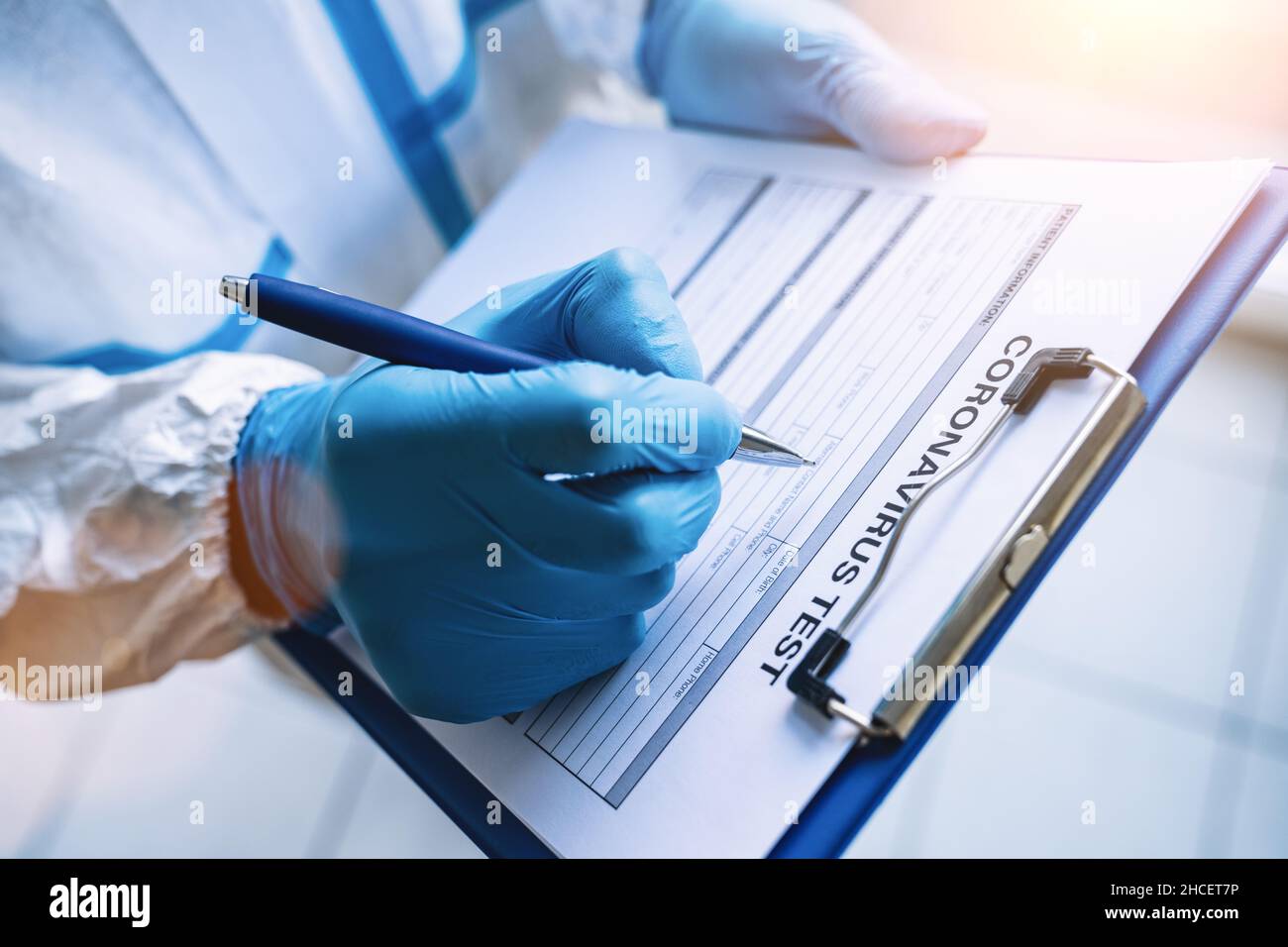 Forscher füllt ein Coronavirus-Testdatenblatt mit Stift in Schutzkleidung in einer Klinik bei der Coronavirus-Epidemie Covid-19 aus Stockfoto