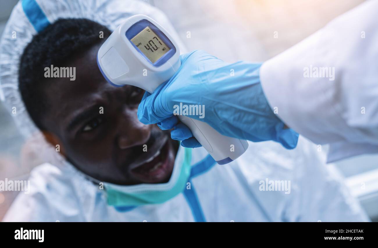 Medizinische Fachkräfte in Schutzkleidung, die kontaktloses Fieber im Covid-19-Testzentrum während der Epidemie des Coronavirus messen Stockfoto