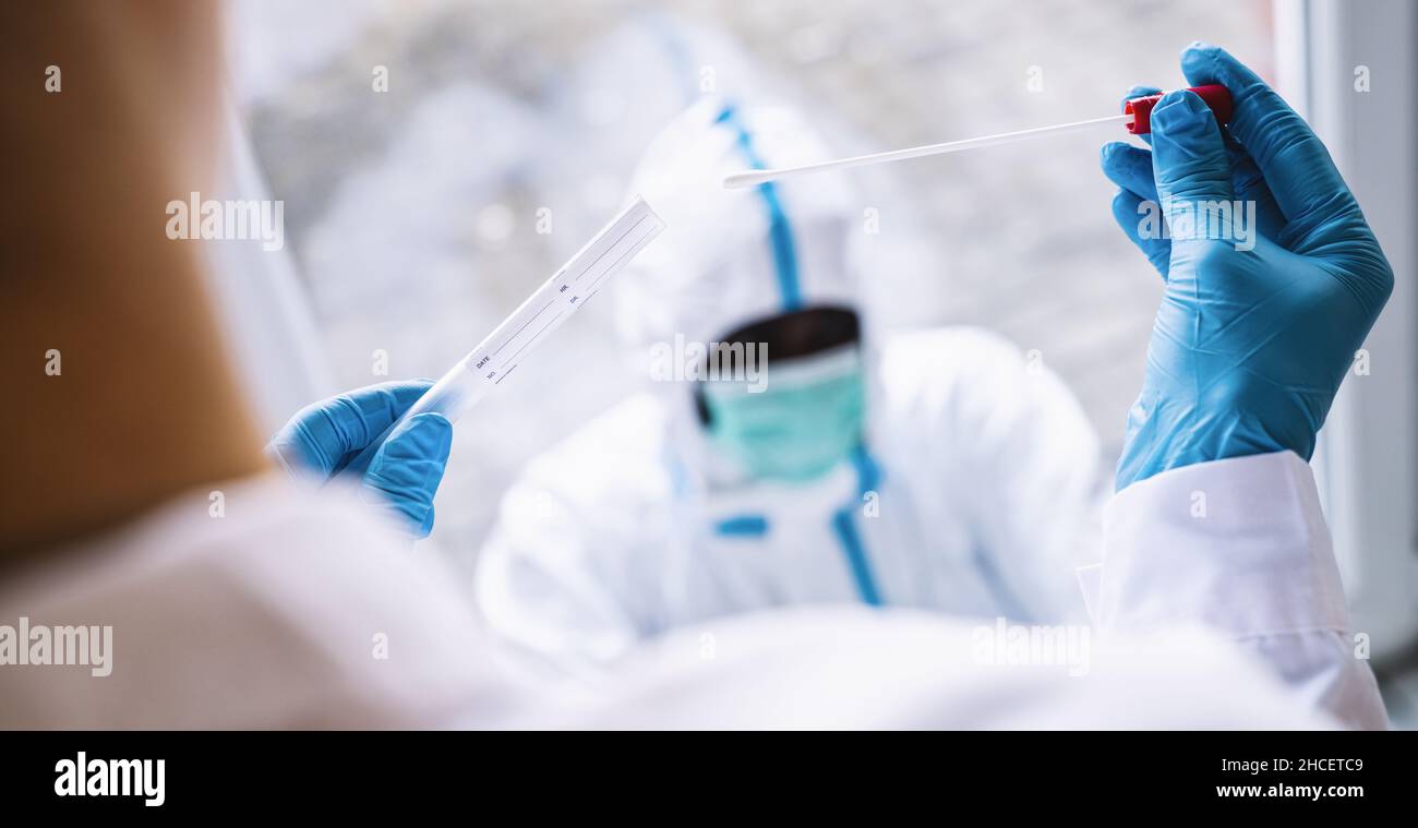 Medizinische Fachkraft in Schutzkleidung nimmt während der Coronavirus-Epidemie den COVID-19 Tupfer-Reagenzglaskasten im Covid-19-Testzentrum ein. PCR-DNA-Tests pro Stockfoto