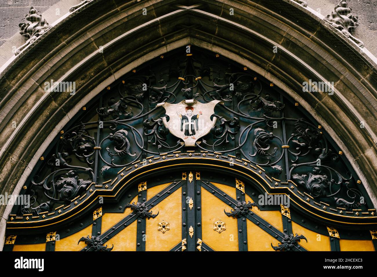 Bogentür mit schmiedeeisernen Dekorelementen und Wappen mit einem Engel in einem alten Gebäude Stockfoto