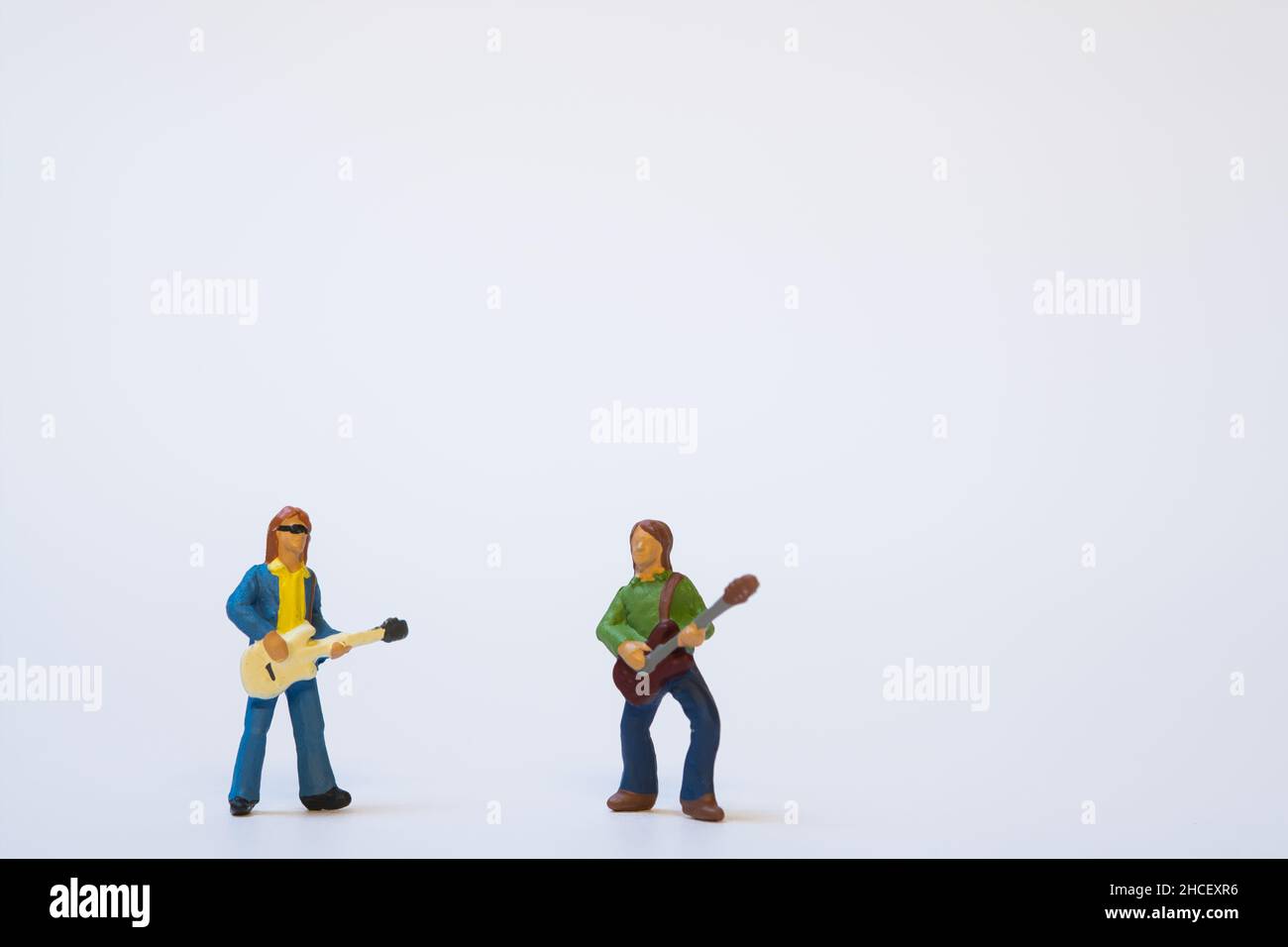 Miniatur-Gitarristen spielen Musik auf weißem Hintergrund - Copy Space Stockfoto