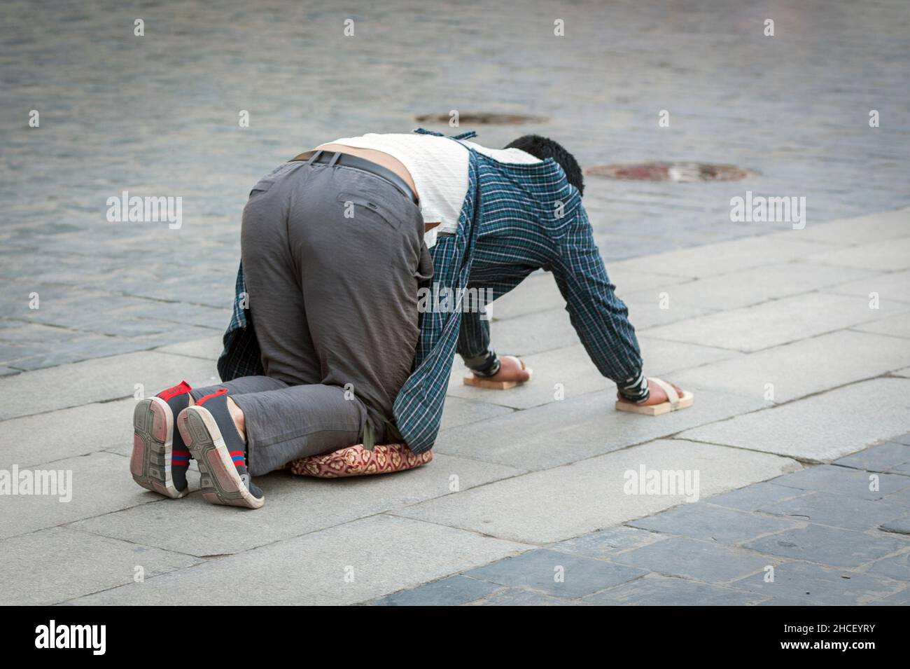 Tibetische Pilgerin, die auf dem Boden liegt, nachdem sie sich niedergewurmt hat. Die 'Barkhor Kora' machen, eine hingebungsvolle Pilgerreise um das Äußere des alten Jokhan Stockfoto