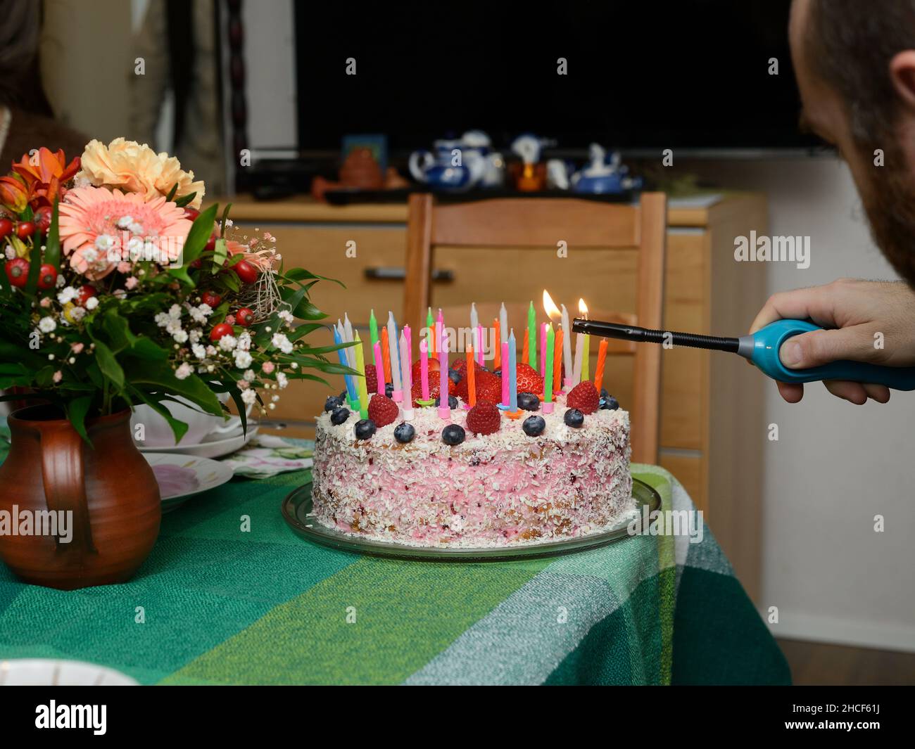 Kerzen auf einem Geburtstagskuchen auf der Party anzünden Stockfoto