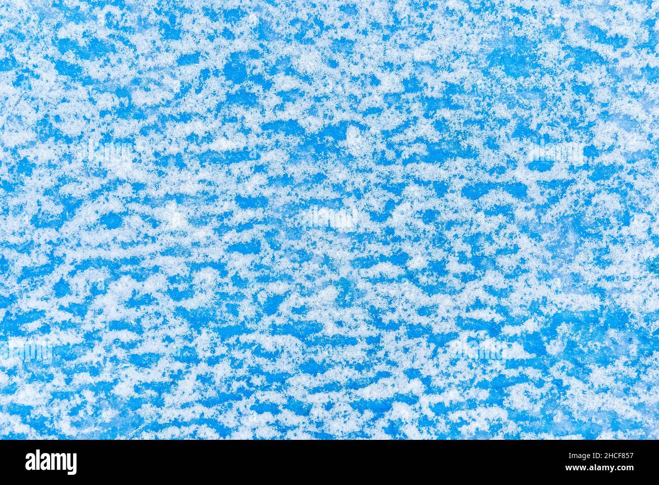 Weißer Schnee abstraktes Muster auf blauer Oberfläche Wandstruktur, Winter, kalter Hintergrund. Stockfoto