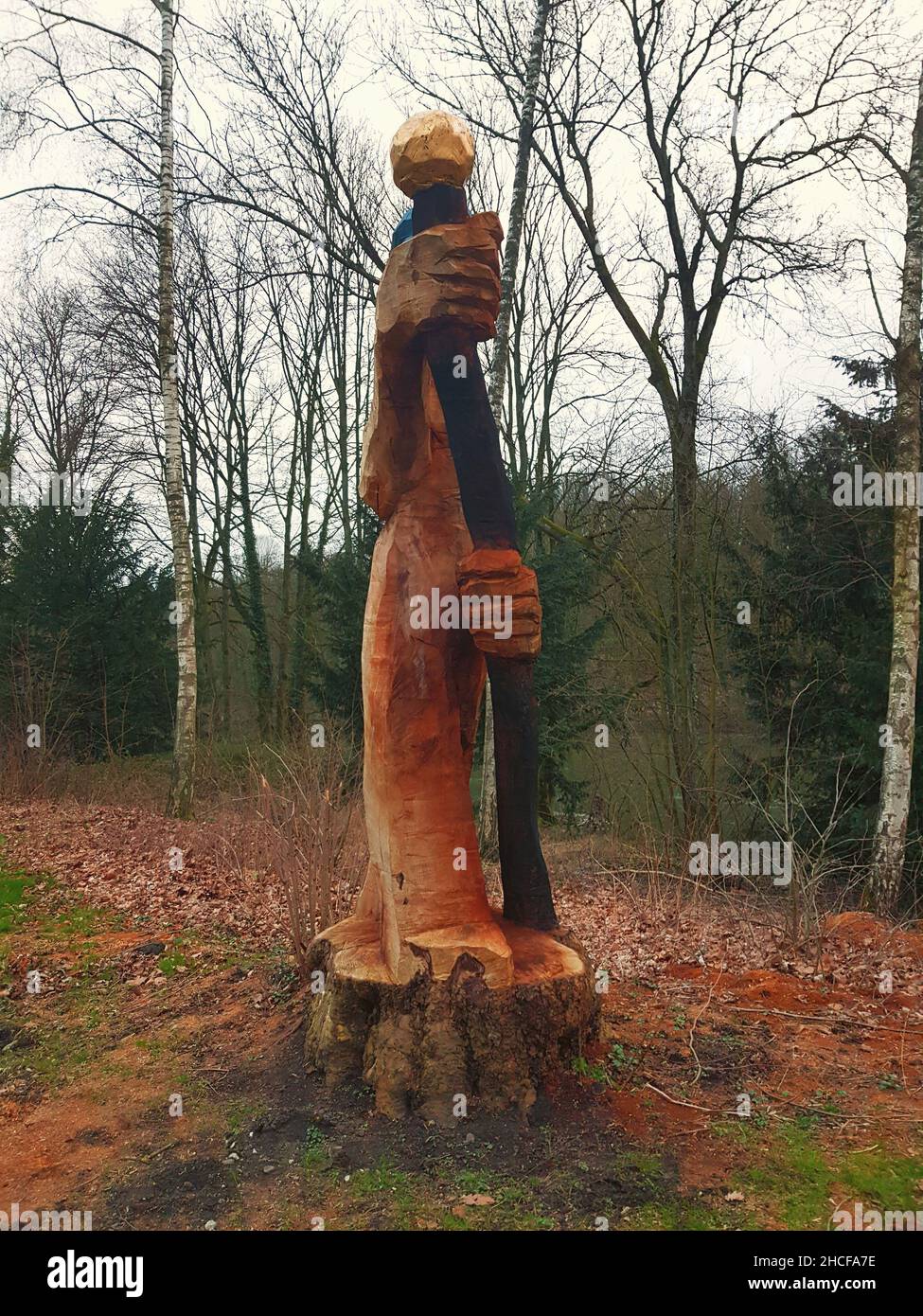 Figur Eichhörnchen mit einer Nuss aus einem Baum auf einem Baumstumpf auf dem Hintergrund des blauen Himmels. Stockfoto