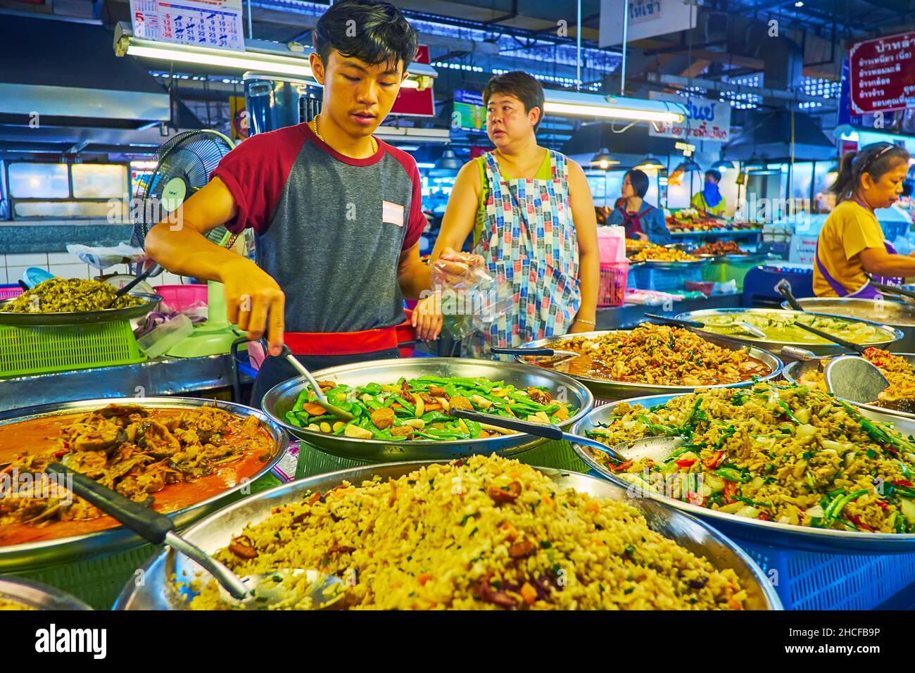 CHIANG MAI, THAILAND - 4. MAI 2019: Tanin Market Stand mit großen Pfannen, gefüllt mit verschiedenen thailändischen Gerichten mit Gemüse, Bohnen, Huhn, Fisch und Reis Stockfoto