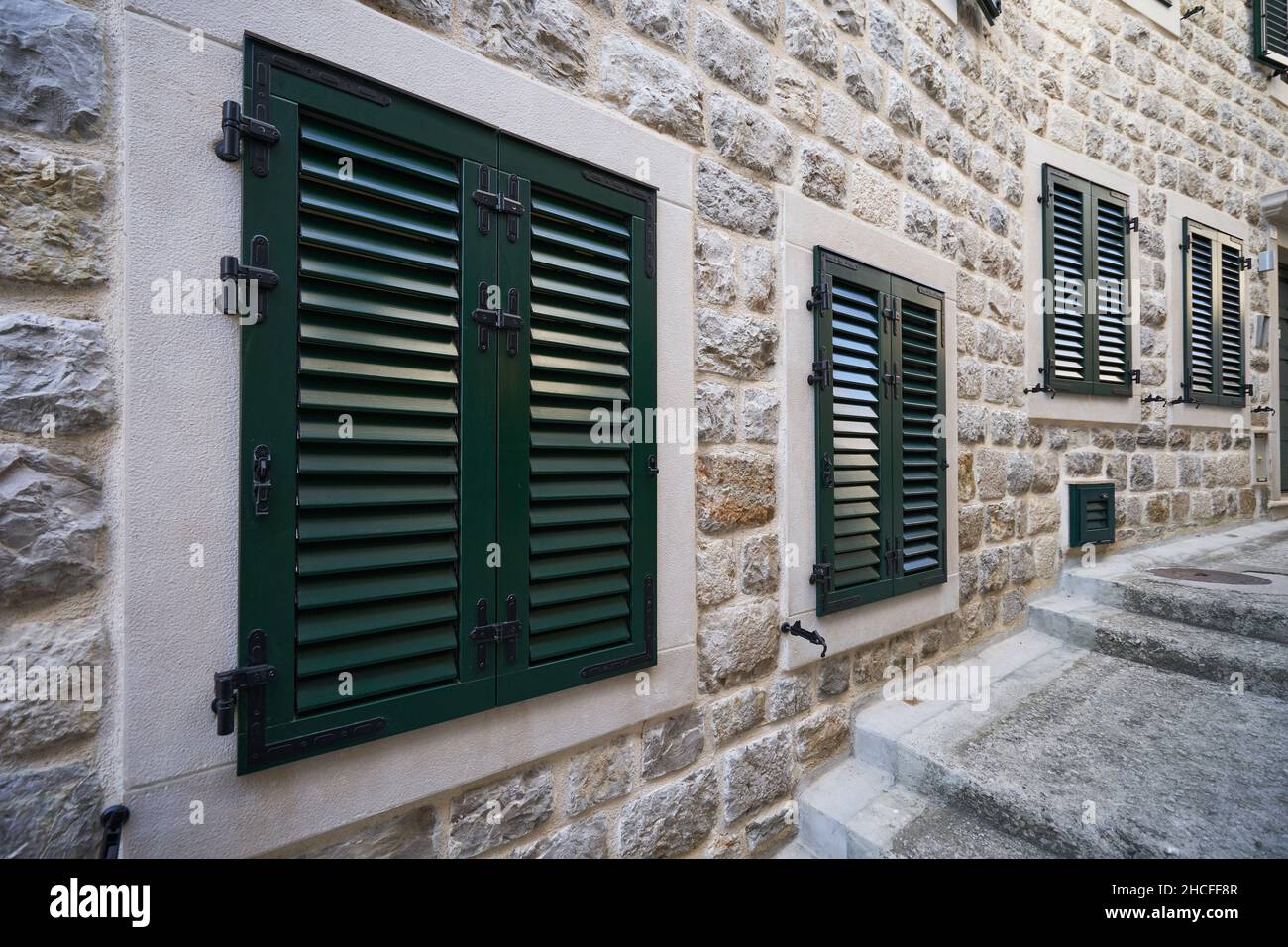 Kunststofffensterläden in einem Wohngebäude mit Steinwänden Stockfoto