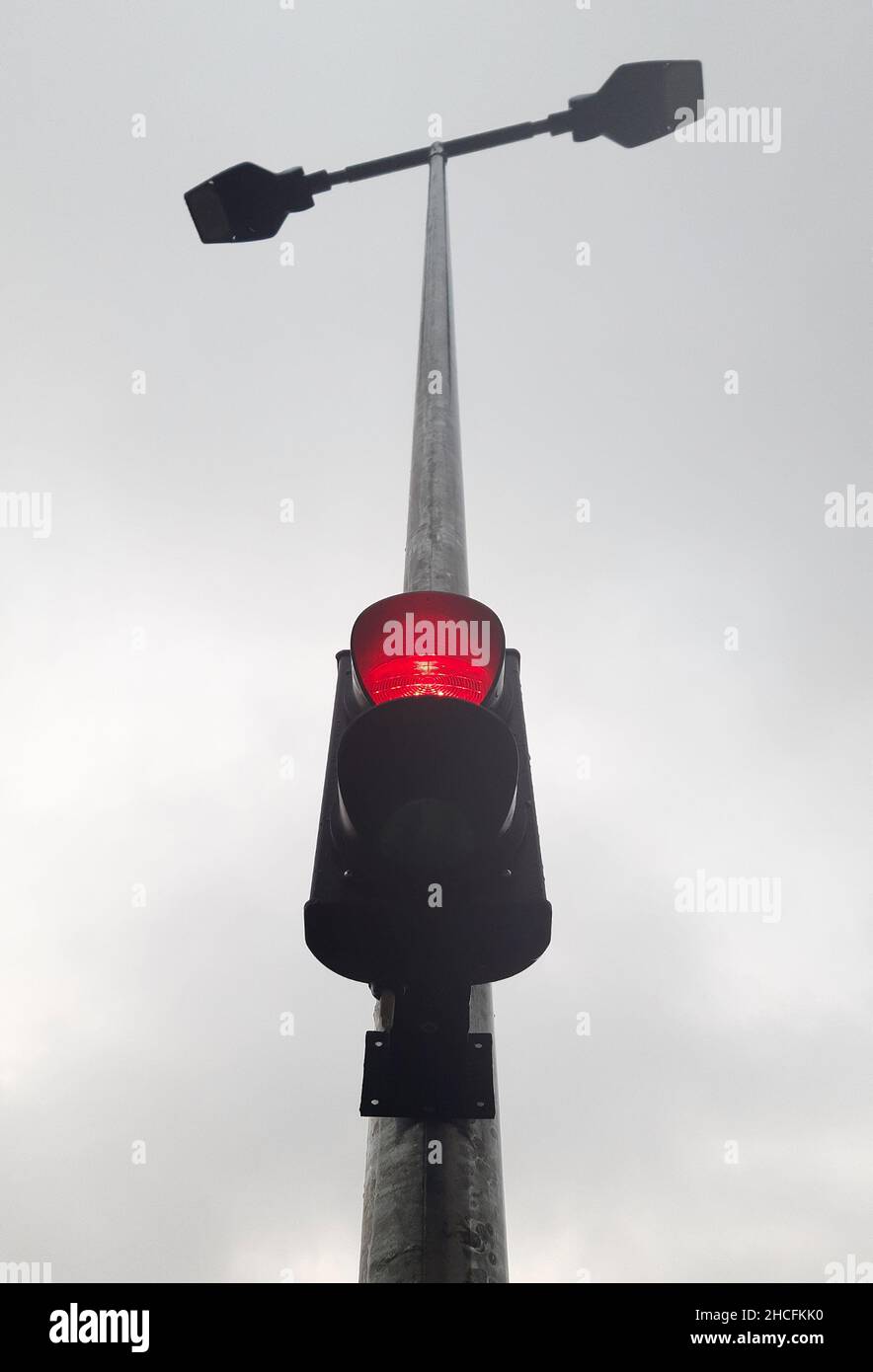 An der Straßenlaterne befindet sich eine zweifarbige Ampel, die rot leuchtet. Von unten fotografiert Stockfoto
