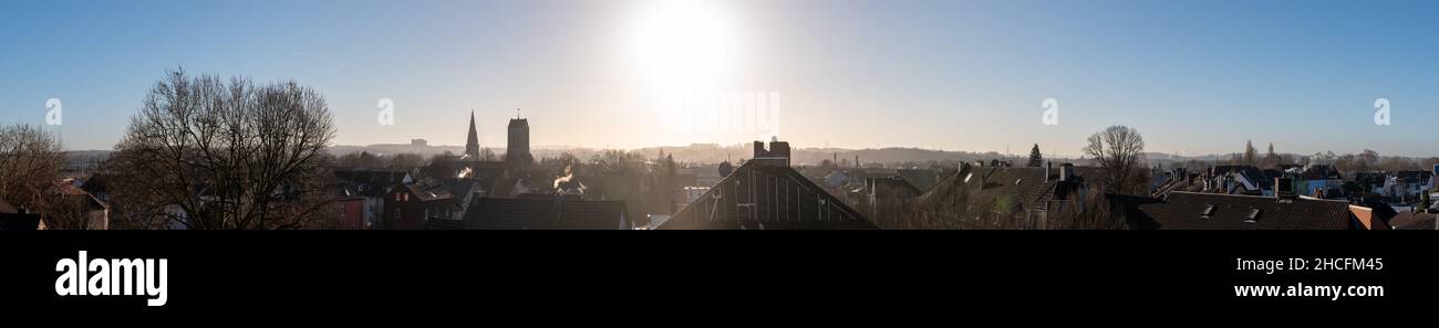Panoramablick über die Dächer von Bochum Langendreer in Deutschland mit den beiden Kirchen und dem Universitätsklinikum im nebligen Hintergrund. Rauchschimm Stockfoto