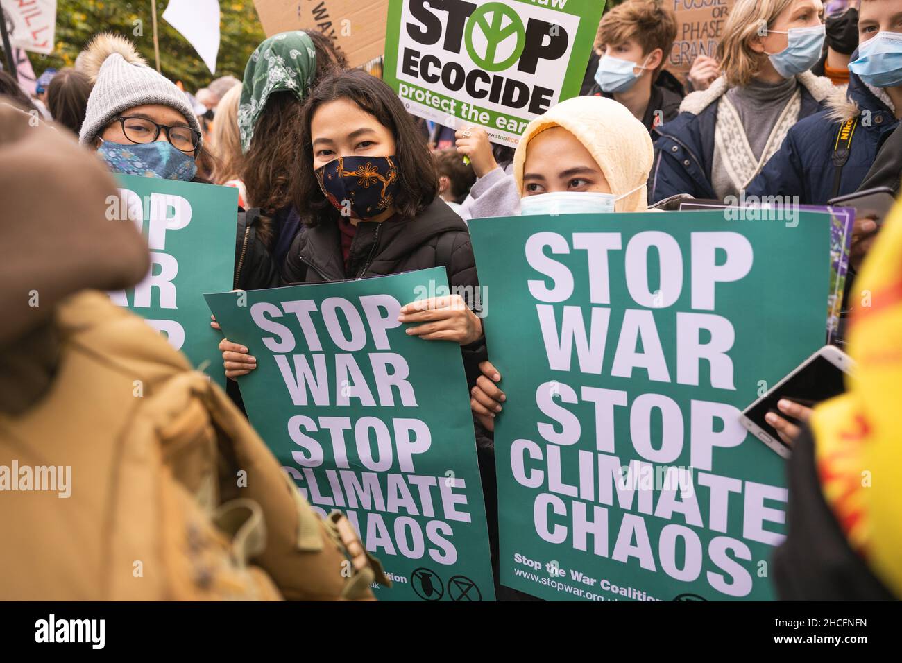 Drei Frauen halten Plakate zum Klimawandel, die sagen: „Stoppt den Krieg Stoppt das Klimachaos“ bei einem Protest Stockfoto