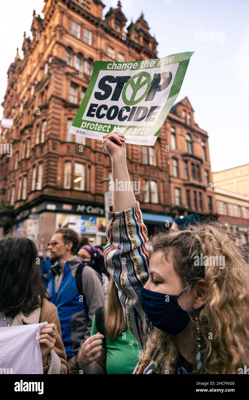 Vertikal eines Protesters, der auf einem Klimaprotest in Glasgow, Schottland, ein Schild mit der Aufschrift „Stop Ecocide“ hält Stockfoto