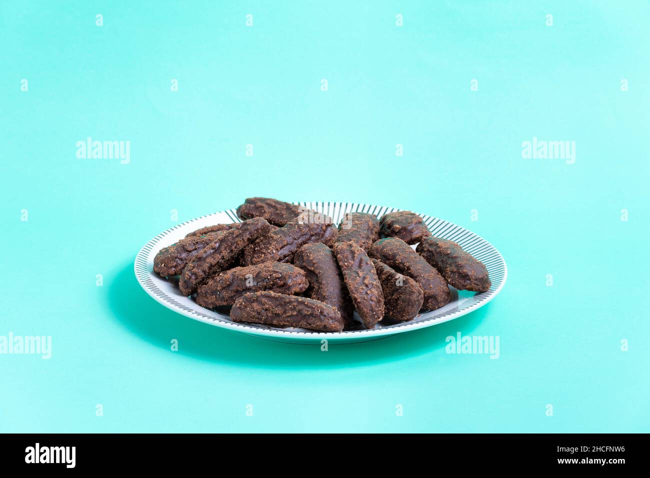 Teller mit in Schokolade getauchten Keksen auf türkisfarbenem Hintergrund Stockfoto