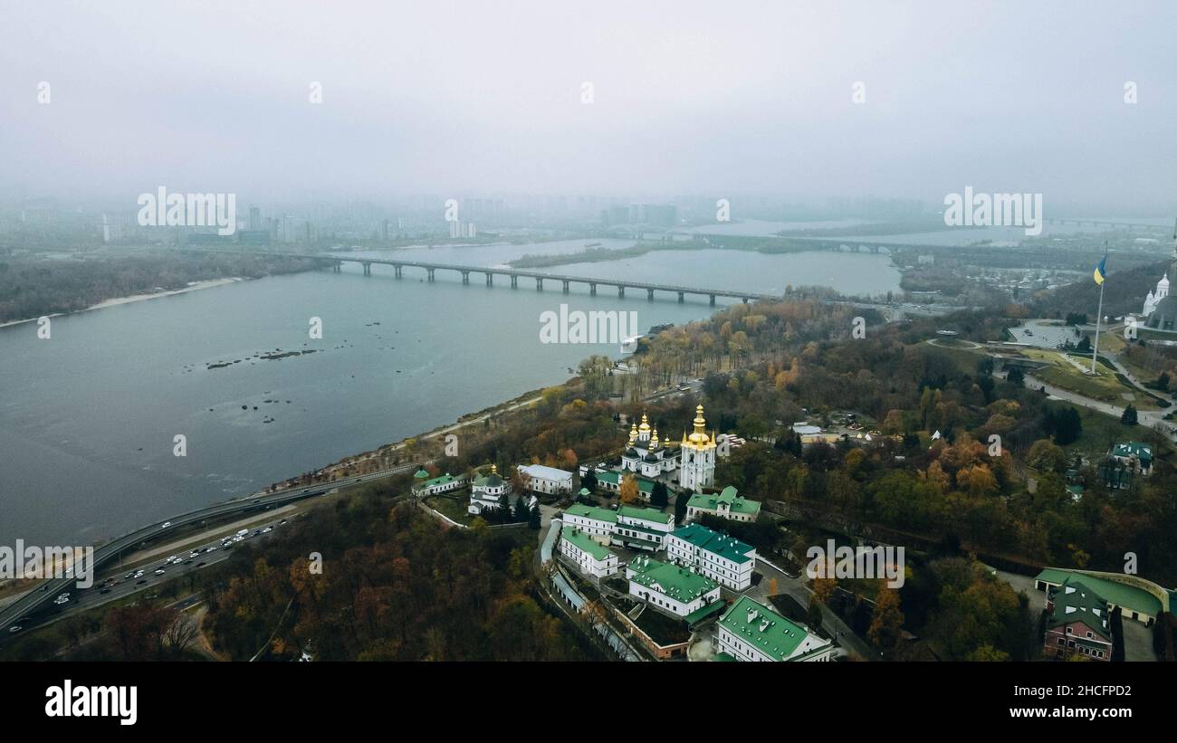 Eine schöne Luft nebligen Blick auf die Kiewer Pechersk Lavra mit Holzbäumen, Brücke über den Fluss in der Ukraine Stockfoto
