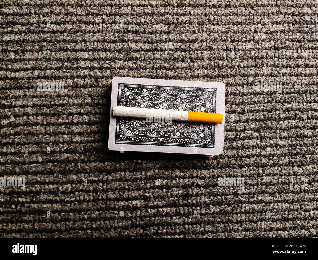 Eine Zigarette auf einer Karte, die auf einem gestrickten Tuch isoliert ist Stockfoto