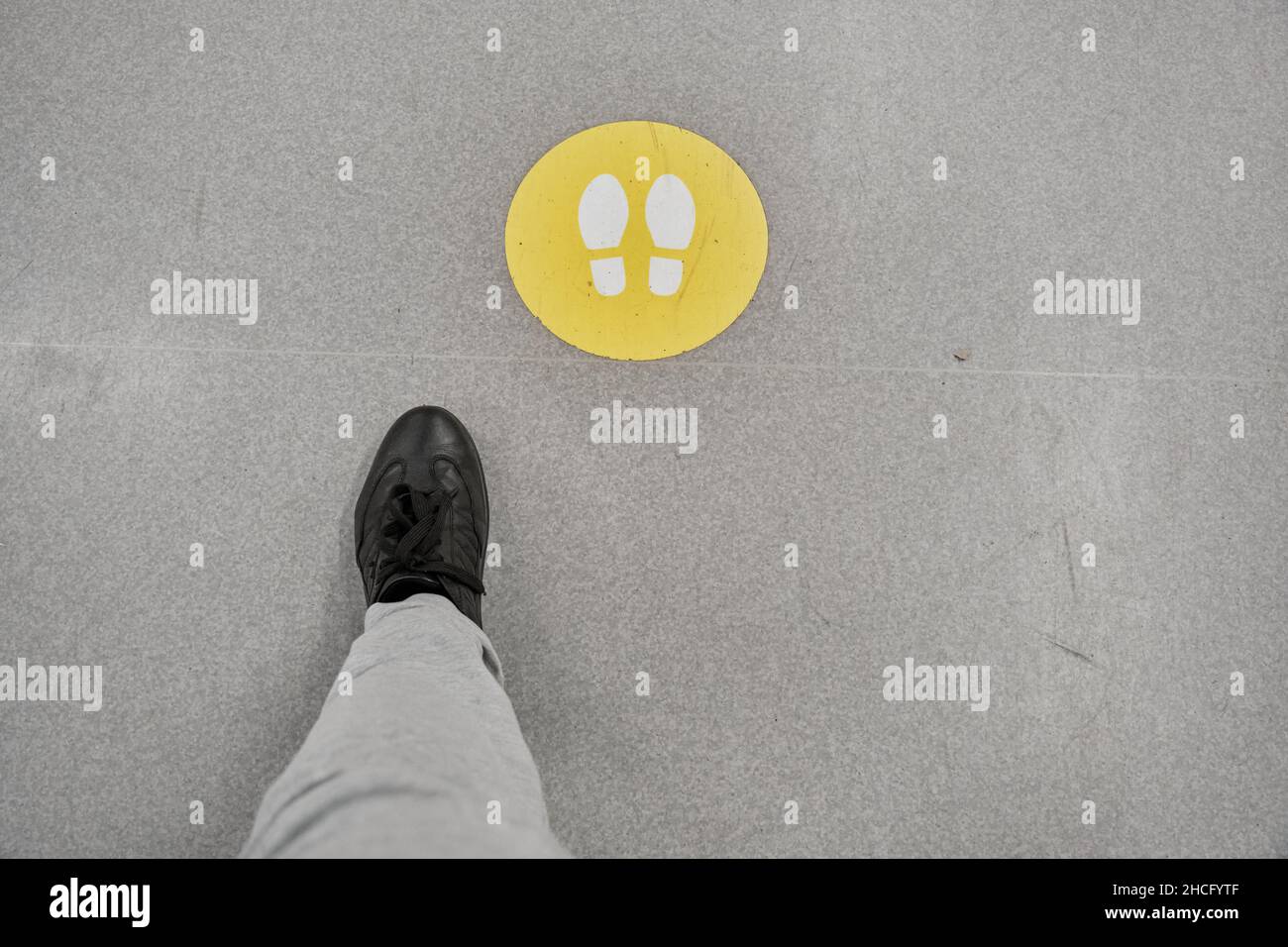 Der Mann in schwarzen Schuhen und weißen Hosen folgt den Schildern auf dem Boden des Einkaufszentrums Stockfoto