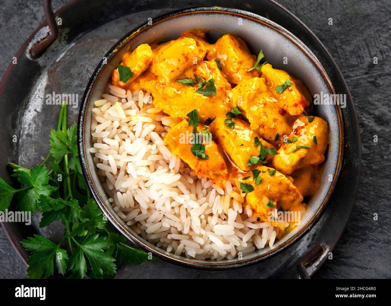 Indisches Butterhuhnfleisch mit Basmati-Reis auf dunklem Hintergrund. Traditionelles hausgemachtes Food-Konzept. Draufsicht Stockfoto