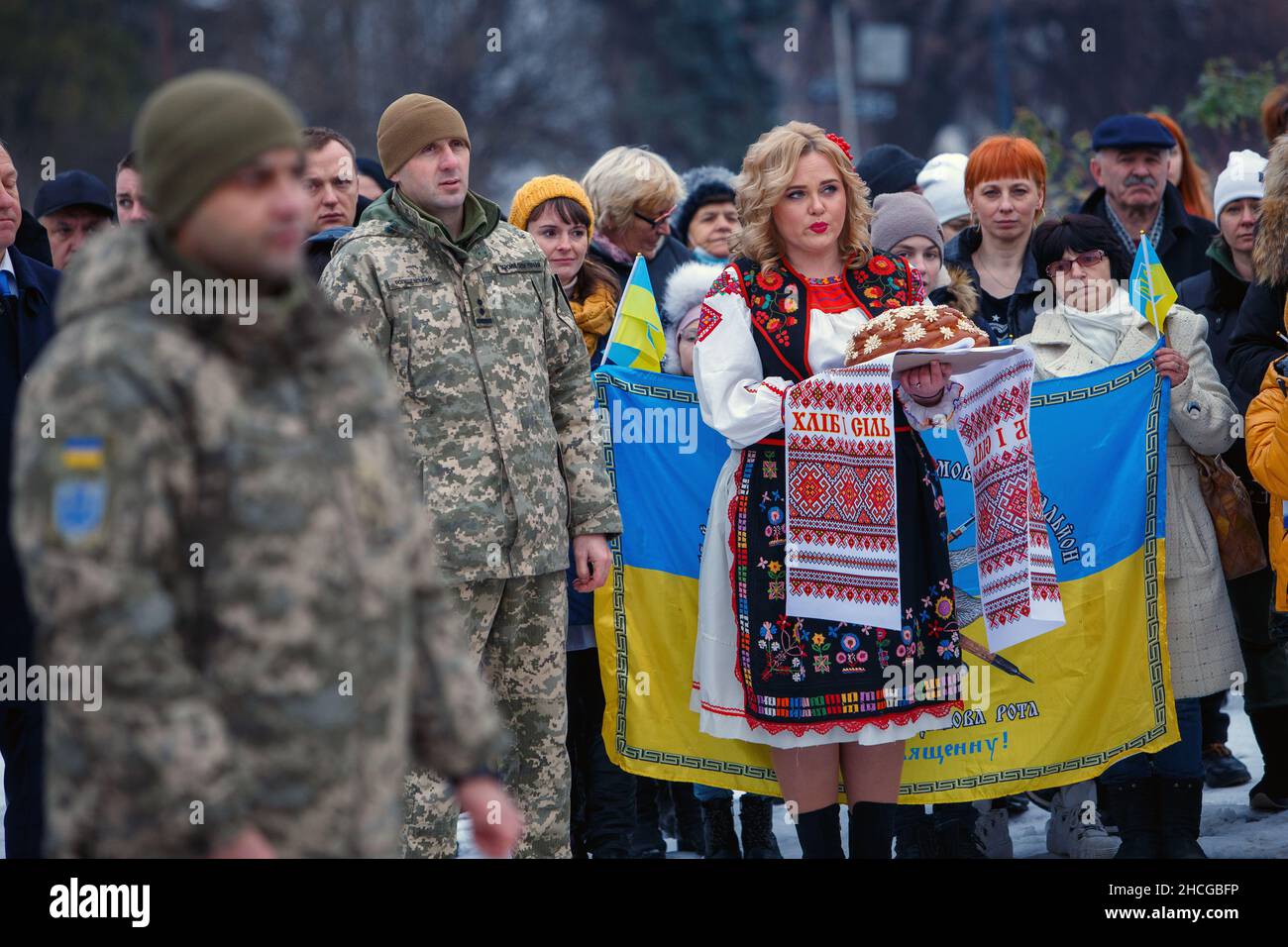 USCHHOROD, UKRAINE - 28. DEZEMBER 2021 - Eine Frau in ukrainischer Kleidung hält einen Korovai mit einem bestickten Handtuch während einer Begrüßungszeremonie auf dem Laiengefieß Stockfoto