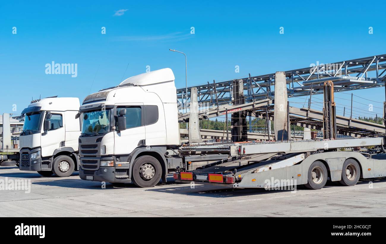 LKW mit Autotransporter Anhänger. Autotransporter stehen in der Nähe der Tore der Verschiffung von Neuwagen in einem Technikwerk. Autotransport. Stockfoto