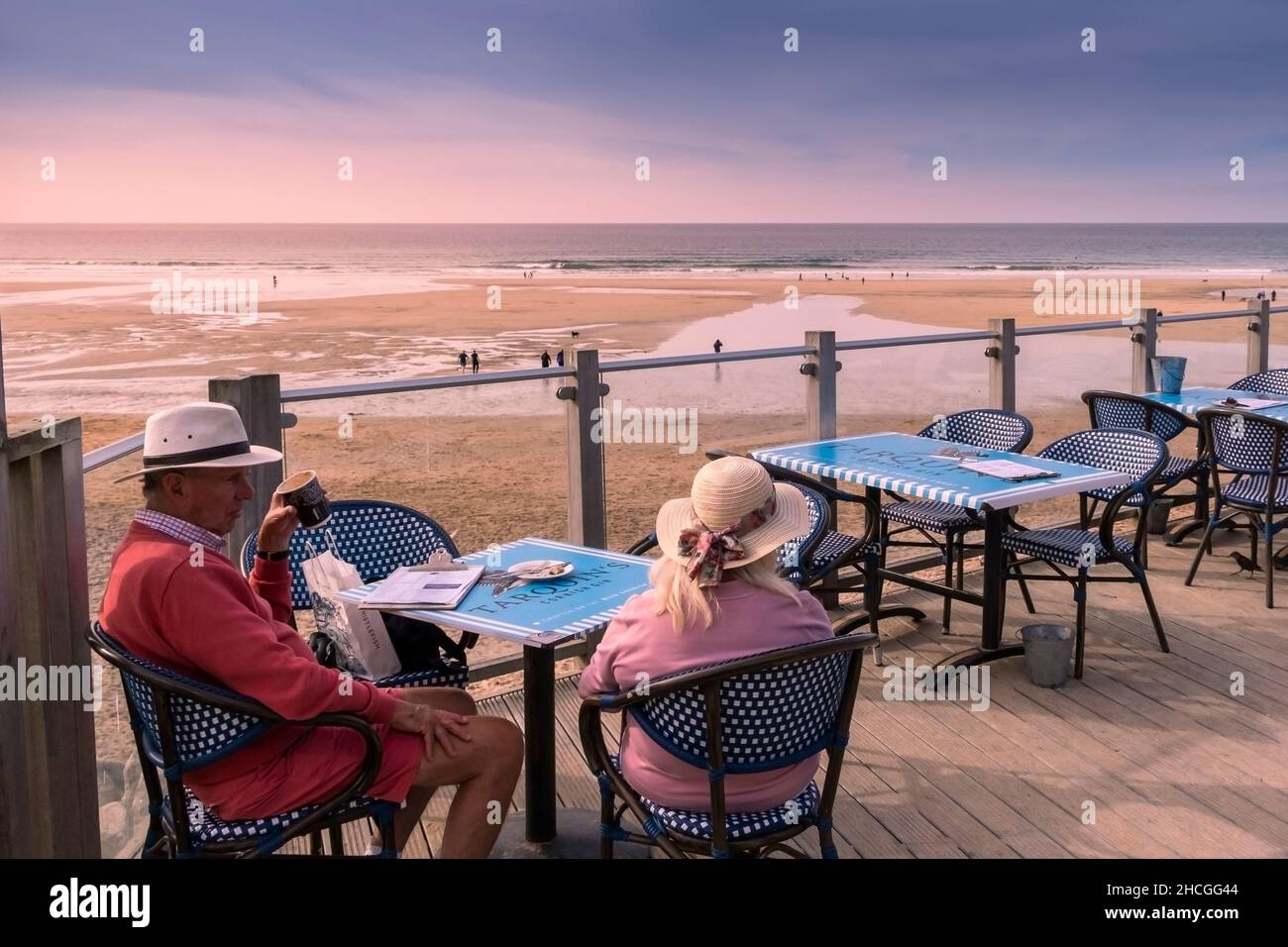Urlauber sitzen auf einem Balkon an der Fistral Beach Bar und genießen einen Kaffee und das Abendlicht in Newquay in Cornwall. Stockfoto