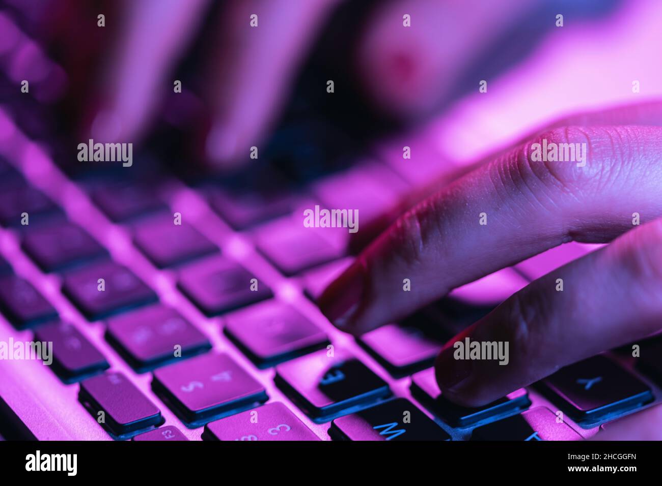 Nahaufnahme Frau Hände tippen auf Laptop-Tastatur, professionelle Online-Gamer Finger auf Notebook-Tastatur in Neon-Farbe, sitzen am Gaming-Schreibtisch Stockfoto
