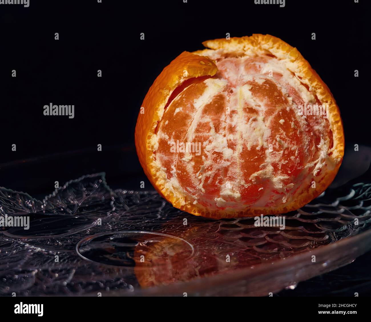 Nahaufnahme einer halbgeschälten Mandarinorange auf schwarzem Hintergrund Stockfoto
