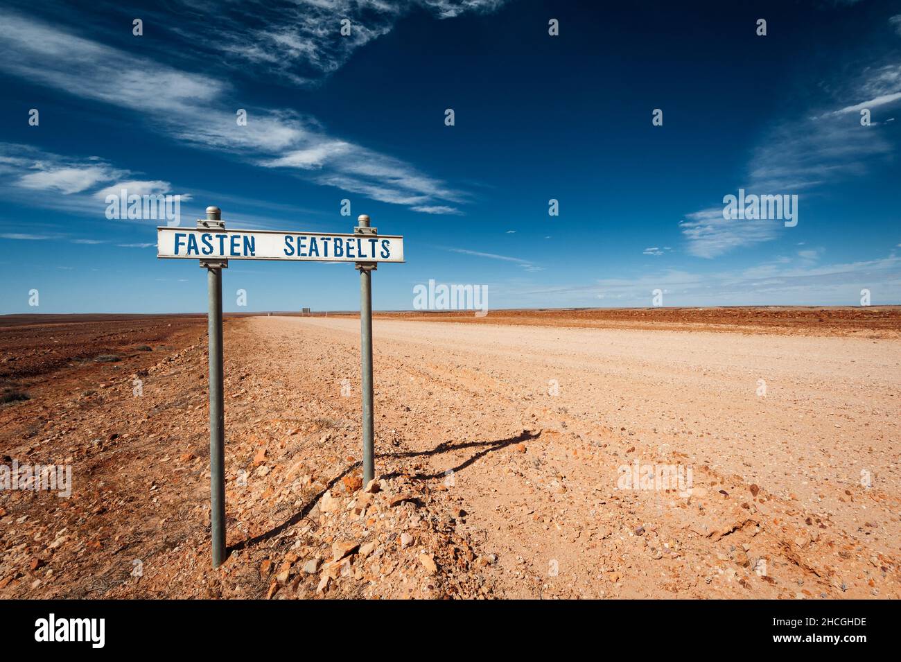 Befestigen Sie das Schild Seatbelt Road an einer Schotterstraße im Outback von Queensland. Stockfoto