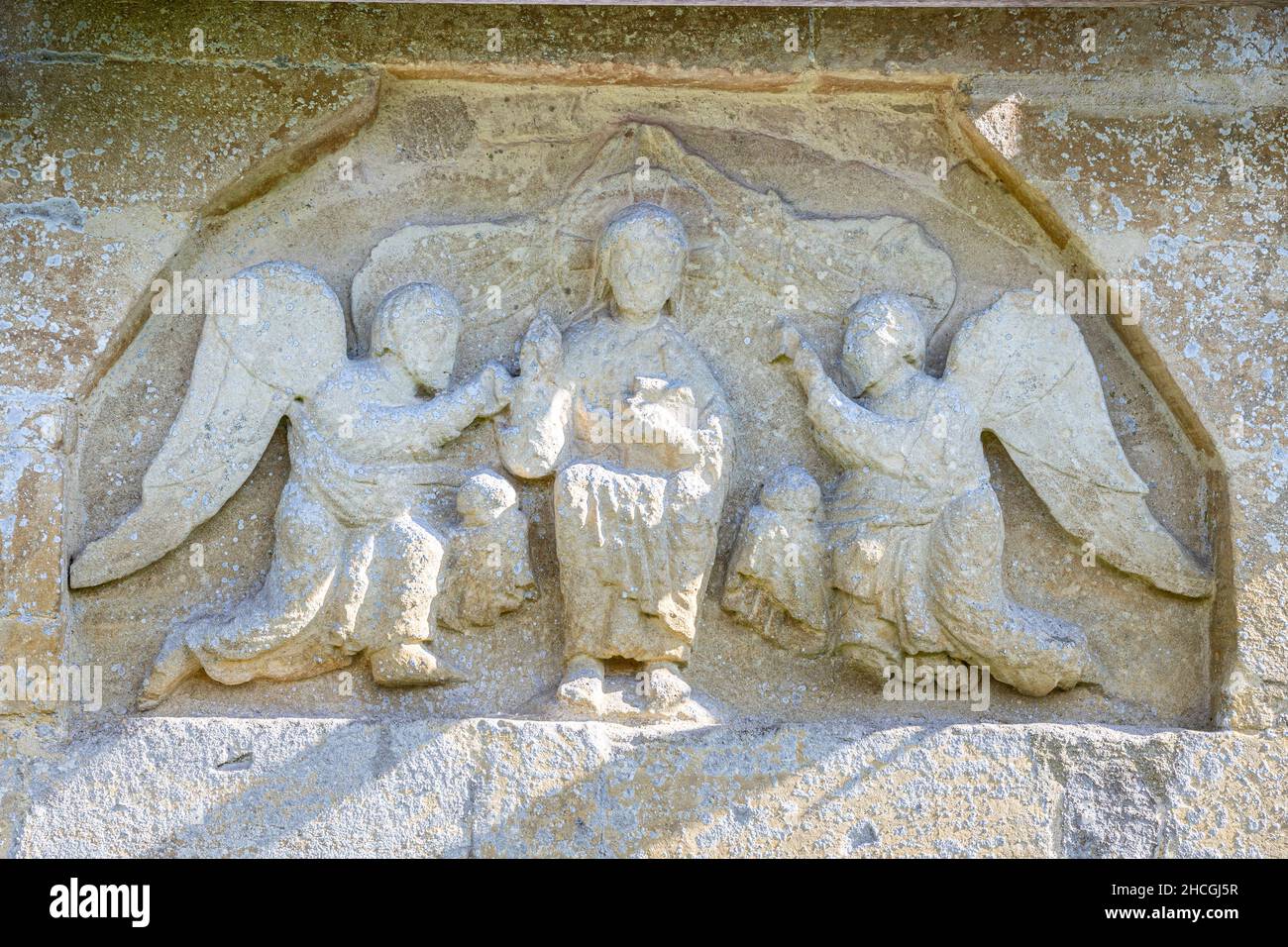 Normannisches Tympanon aus dem 12th. Jahrhundert, das Christus und 2 dienende Engel in der Wand der St. Peters-Kirche im Cotswold-Dorf Little Barrington in Großbritannien zeigt Stockfoto