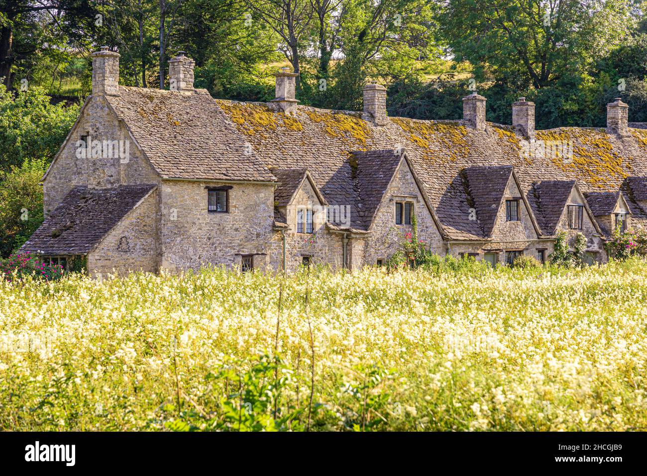 Abendlicht fällt auf Arlington Row, Weber-Hütten aus dem 14th. Jahrhundert im Cotswold-Dorf Bibury, Gloucestershire, Großbritannien. Blick über Rack Isle. Stockfoto