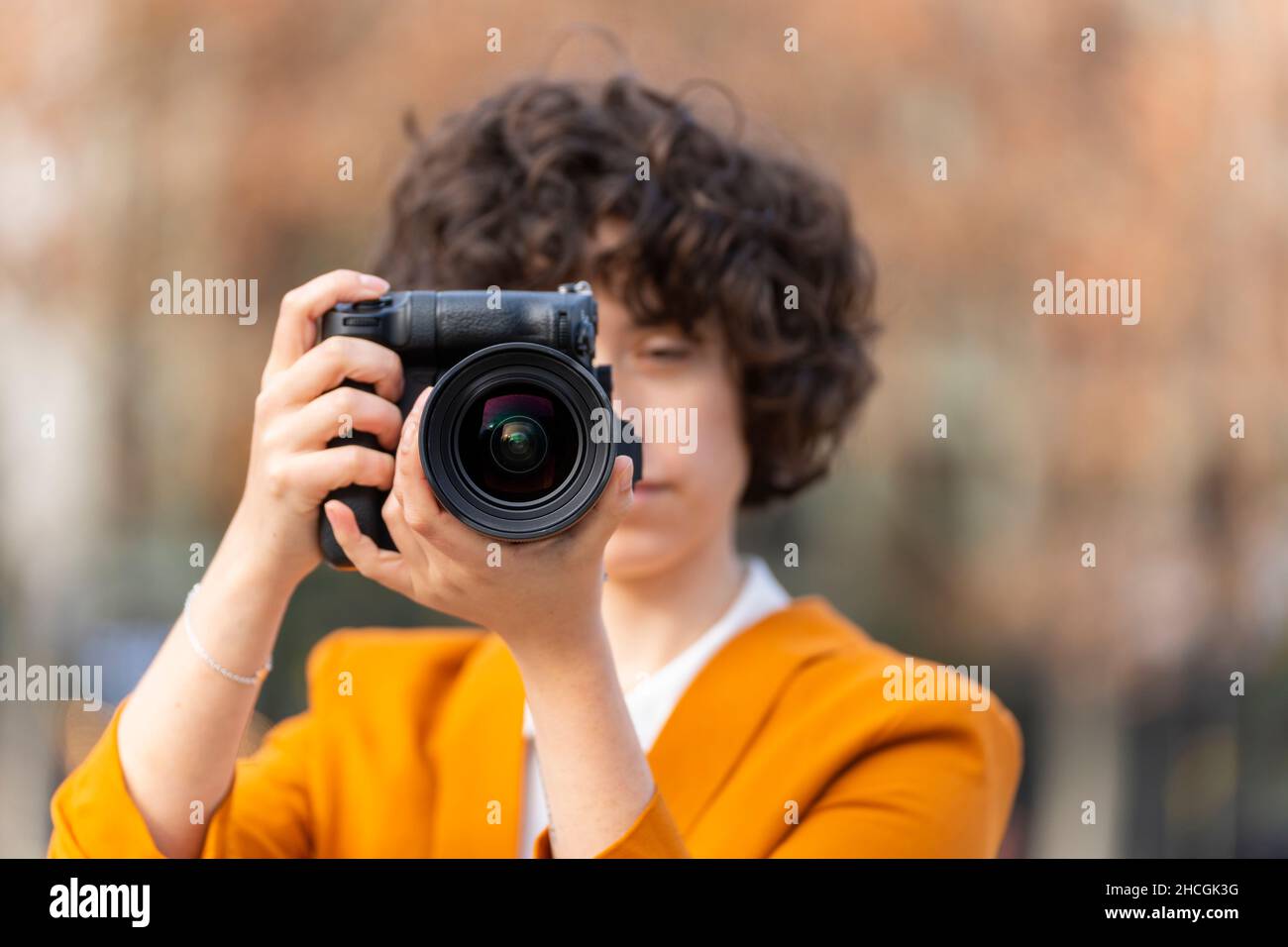 Junge Brünette Frau mit lockigen Haaren, die mit ihrer großen Kamera ein Foto gemacht hat Stockfoto