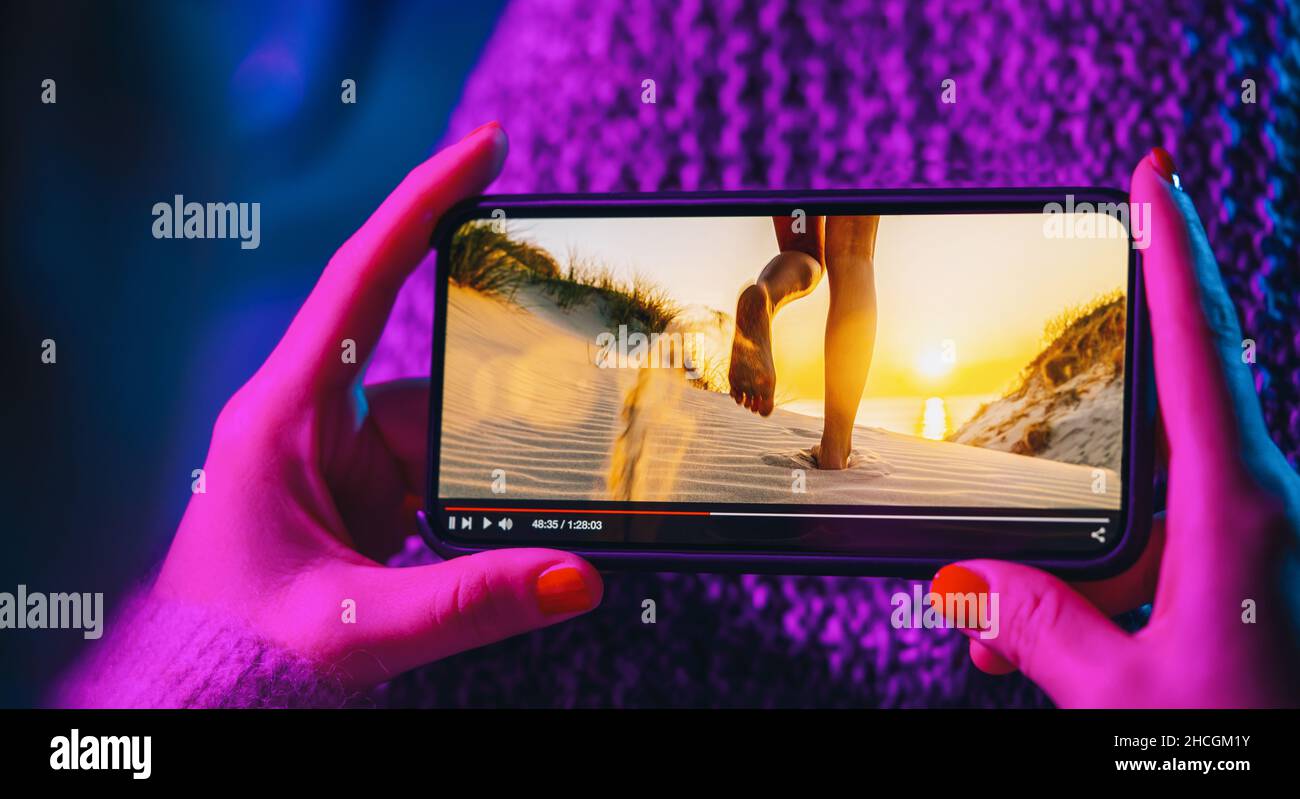 Online-Film-Stream mit Smartphone. Frau, die sich mit einem imaginären Videoplayer einen Film auf einem Mobiltelefon ansieht. Stockfoto
