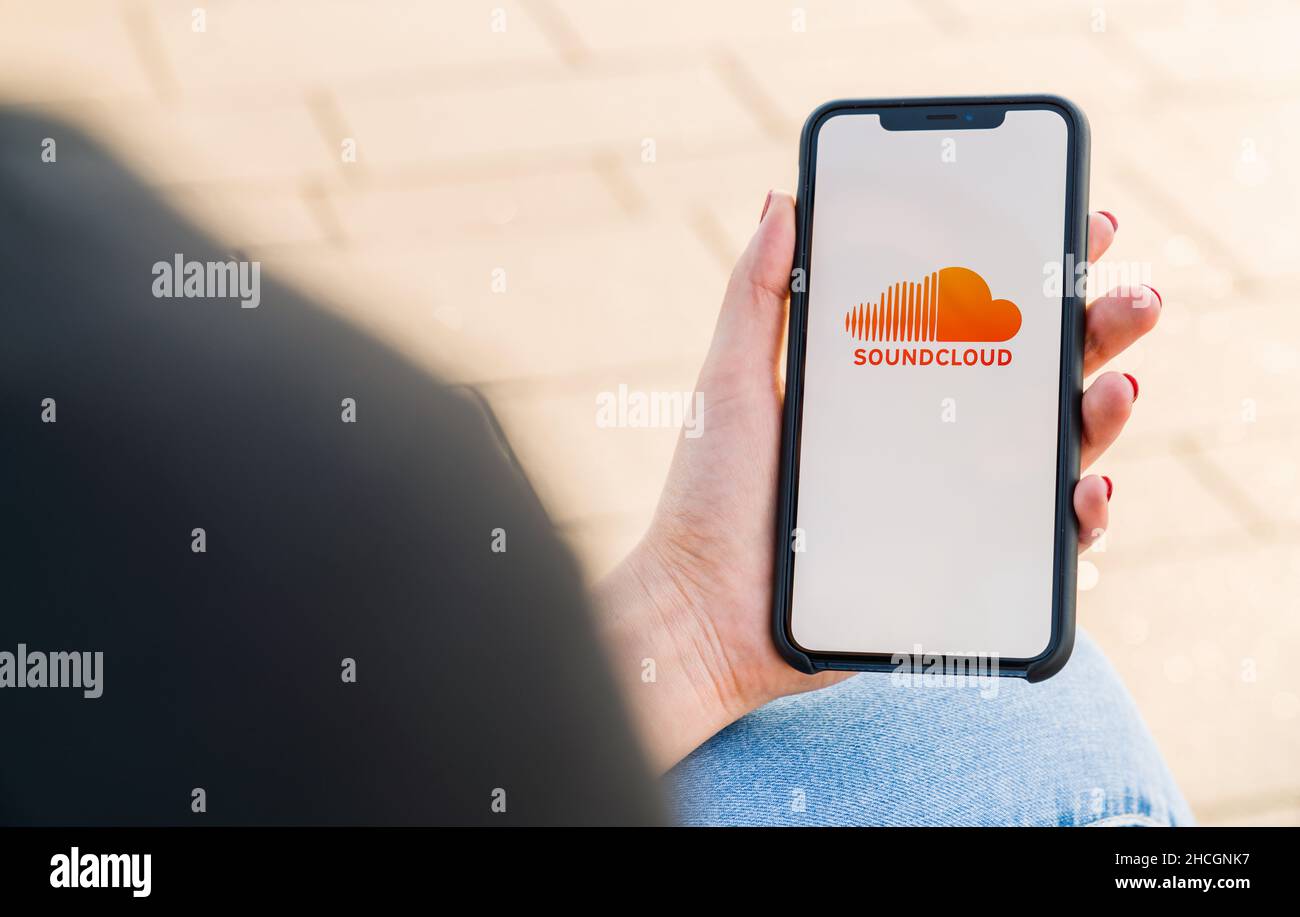 Frau mit der Hand des iphone XS, die die soundcloud Music Streaming App in der Stadt öffnet. Streamen von Musik über das Internet Stockfoto