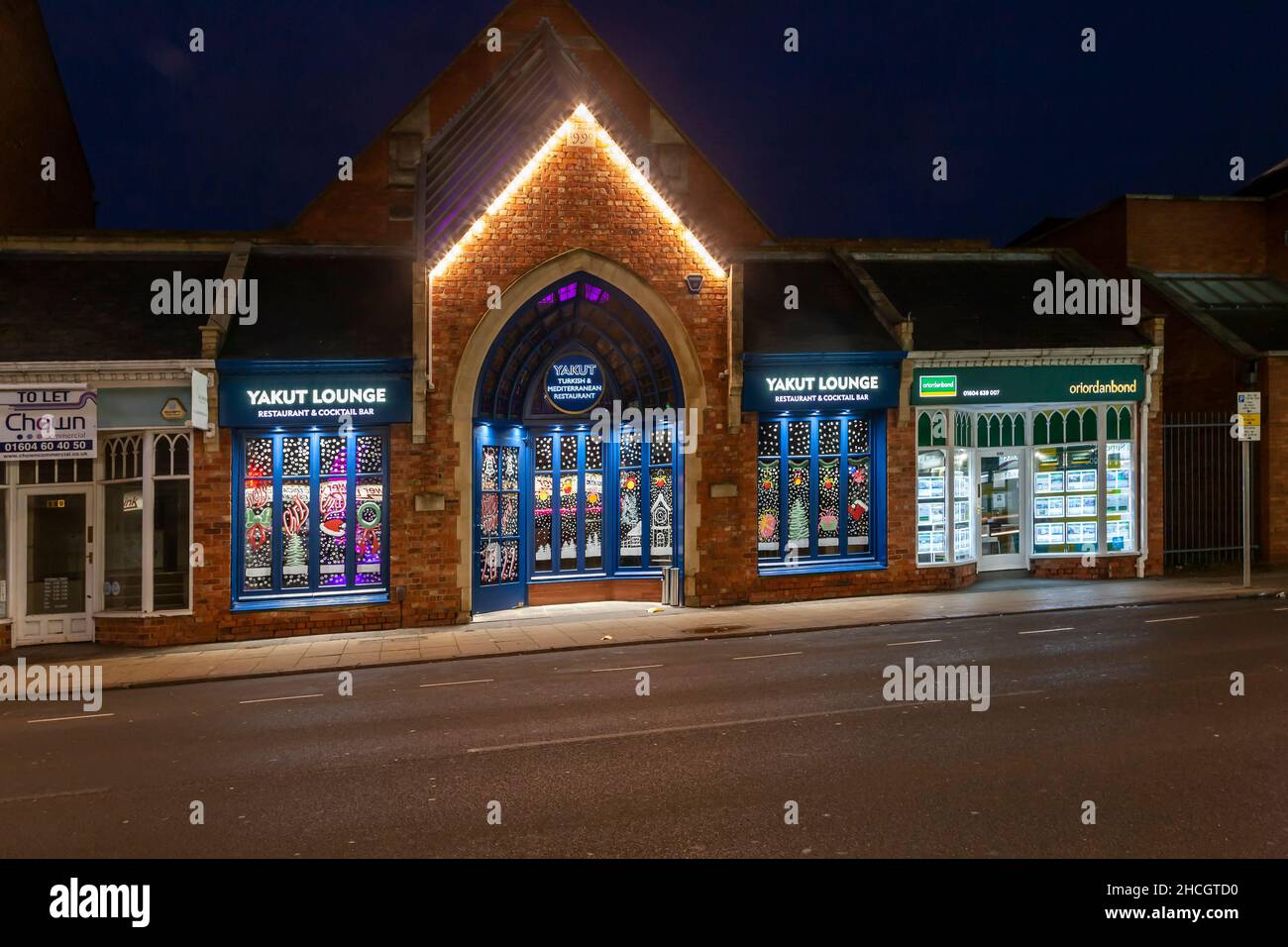 Die Yakut Lounge und die Geschäfte lassen sich am frühen Morgen auf der Wellingborough Road, Northampton, England, Großbritannien, erhellen Stockfoto