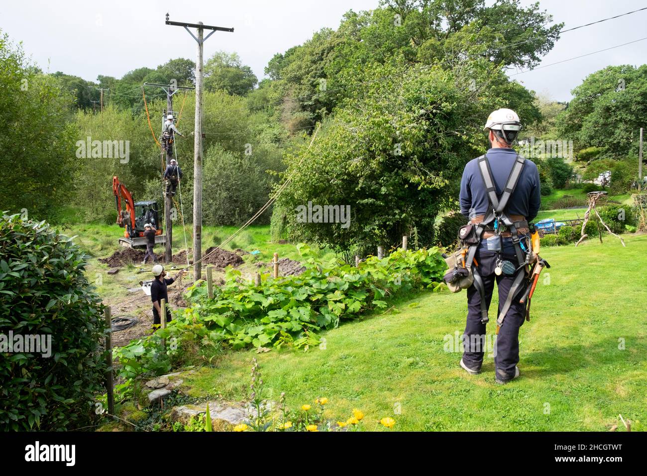 Stromleitungen Männer, die mit Ausrüstung und Bagger arbeiten und im Sommer einen neuen Strommast einrichten Carmarthenshire Wales UK 2021 Großbritannien KATHY DEWITT Stockfoto