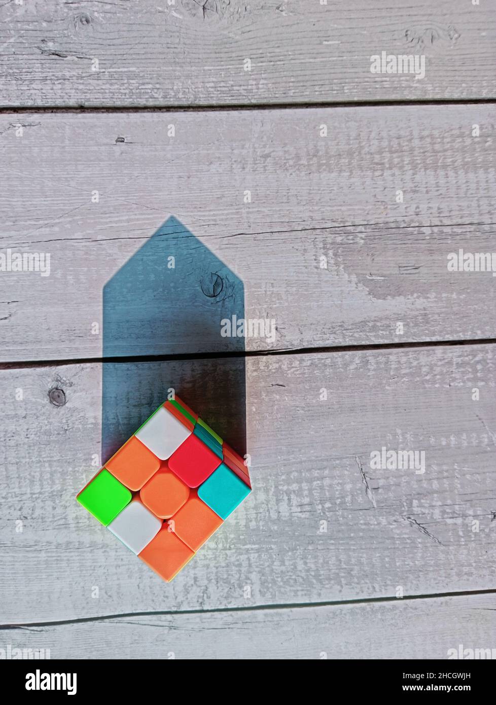 Eine unsortierte Puzzle-Box im Sonnenlicht. Das Objekt ist in einer Holzoberfläche platziert und das Sonnenlicht schuf einen dreieckigen oberen Schatten Stockfoto