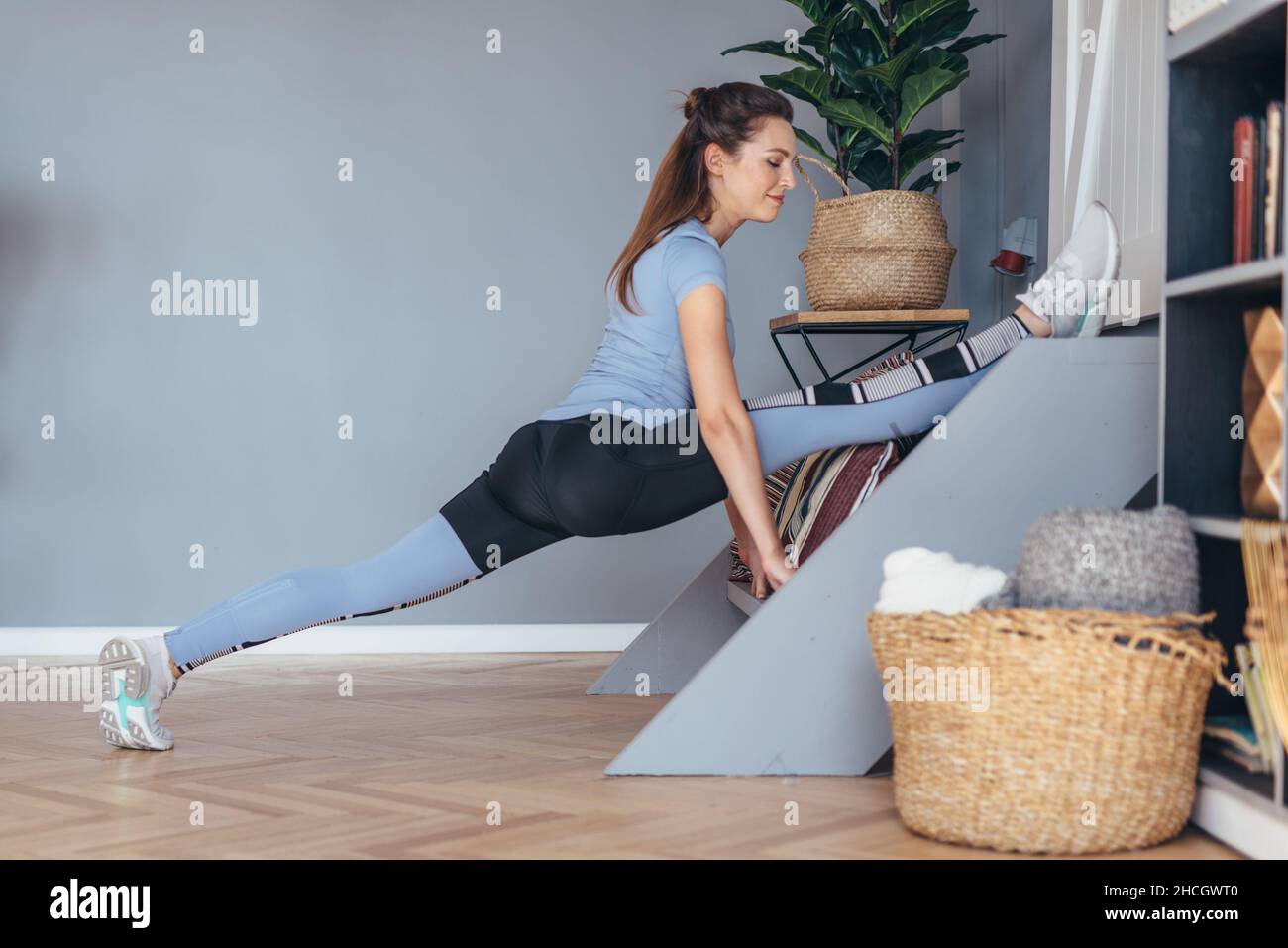 Flexible Frau macht vorne Split Stretching-Übung zu Hause Stockfoto