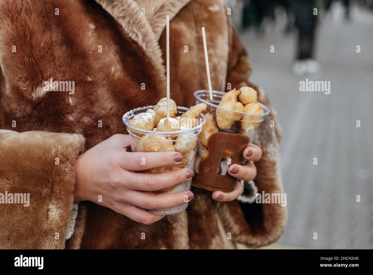 Nahaufnahme einer Frau, die auf dem weihnachtsmarkt zwei Portionen festliches Gebäck in der Hand hält Stockfoto