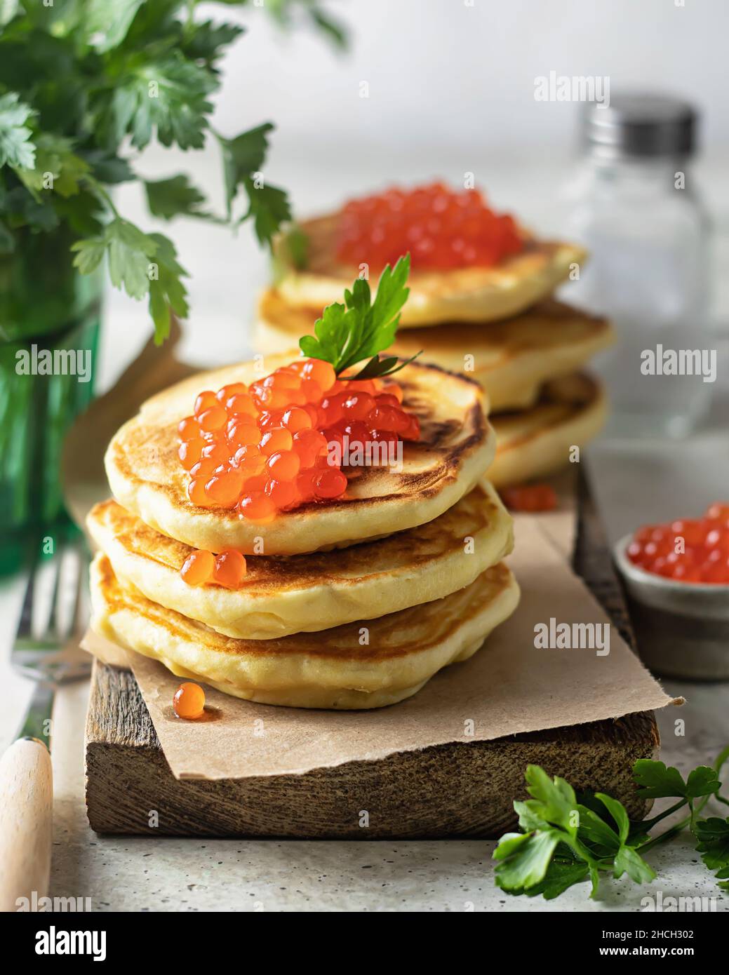 Pfannkuchen mit rotem KaviarPfannkuchen mit rotem Kaviar auf einem Holzbrett serviert. Ein klassisches Gericht für den Urlaub in Maslenitsa Stockfoto