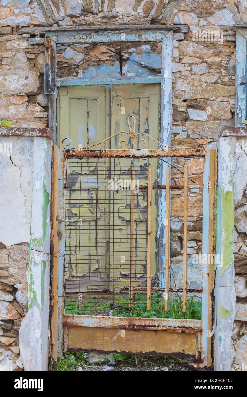 Heruntergekommenes Tor. Abgelegen. Verlassene alte Gebäude mit verfallener grüner Eingangstür und rostigem Tor. Stockbild Stockfoto