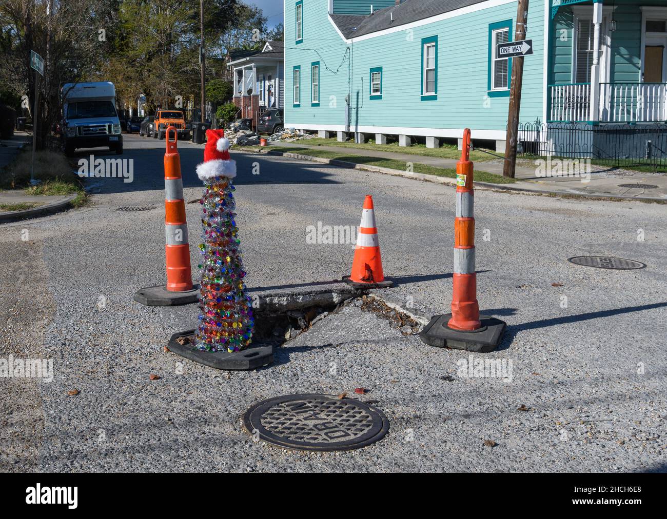 NEW ORLEANS, LA, USA - 24. DEZEMBER 2021: Schlagloch mit vier Verkehrskegeln, einer davon mit Weihnachtsschmuck bedeckt Stockfoto