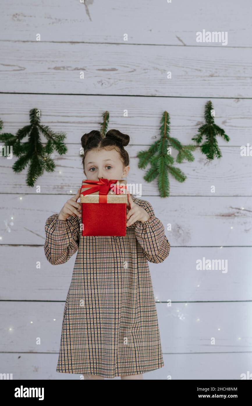 Mädchen mit Weihnachtsgeschenk vor einer weihnachtlichen Kulisse Stockfoto