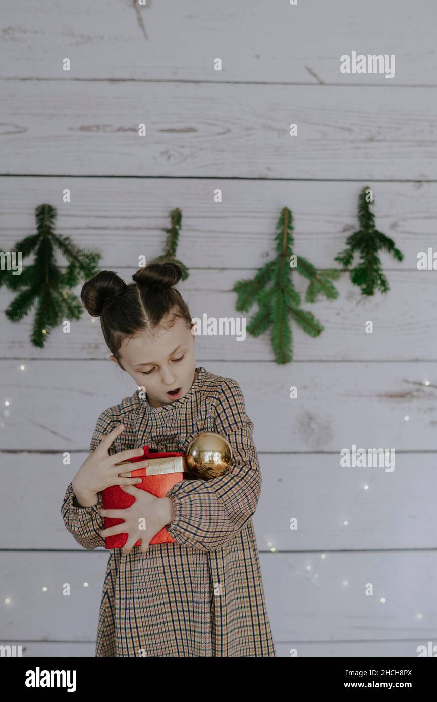 Mädchen mit Weihnachtsgeschenk vor einer weihnachtlichen Kulisse Stockfoto