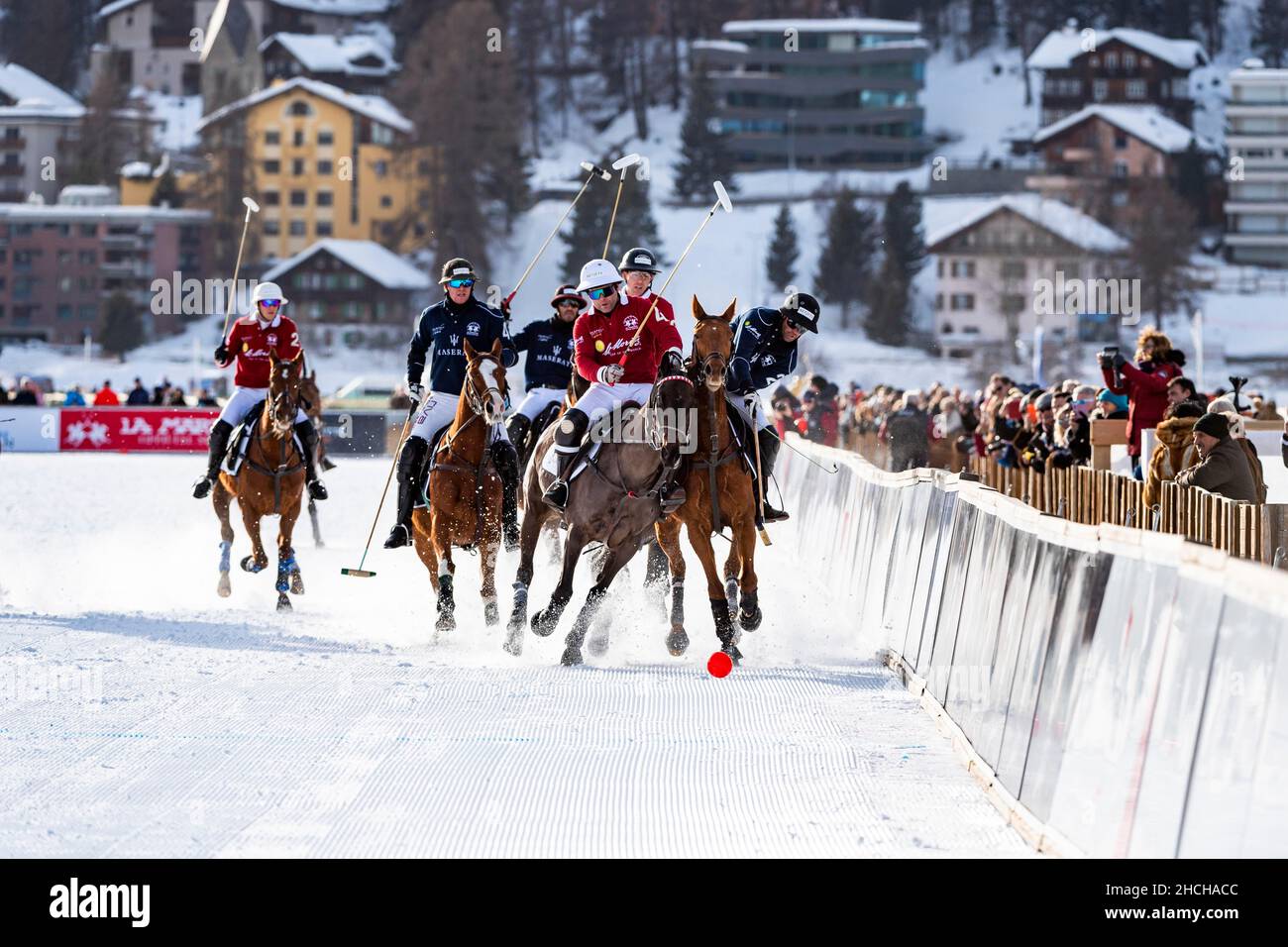 Spieler vom Team Maserati (blau) und Spieler vom Team St. Moritz (rot) kämpfen mit voller körperlicher Anstrengung auf der Schiene um den Ball, 36th Snow Polo Stockfoto