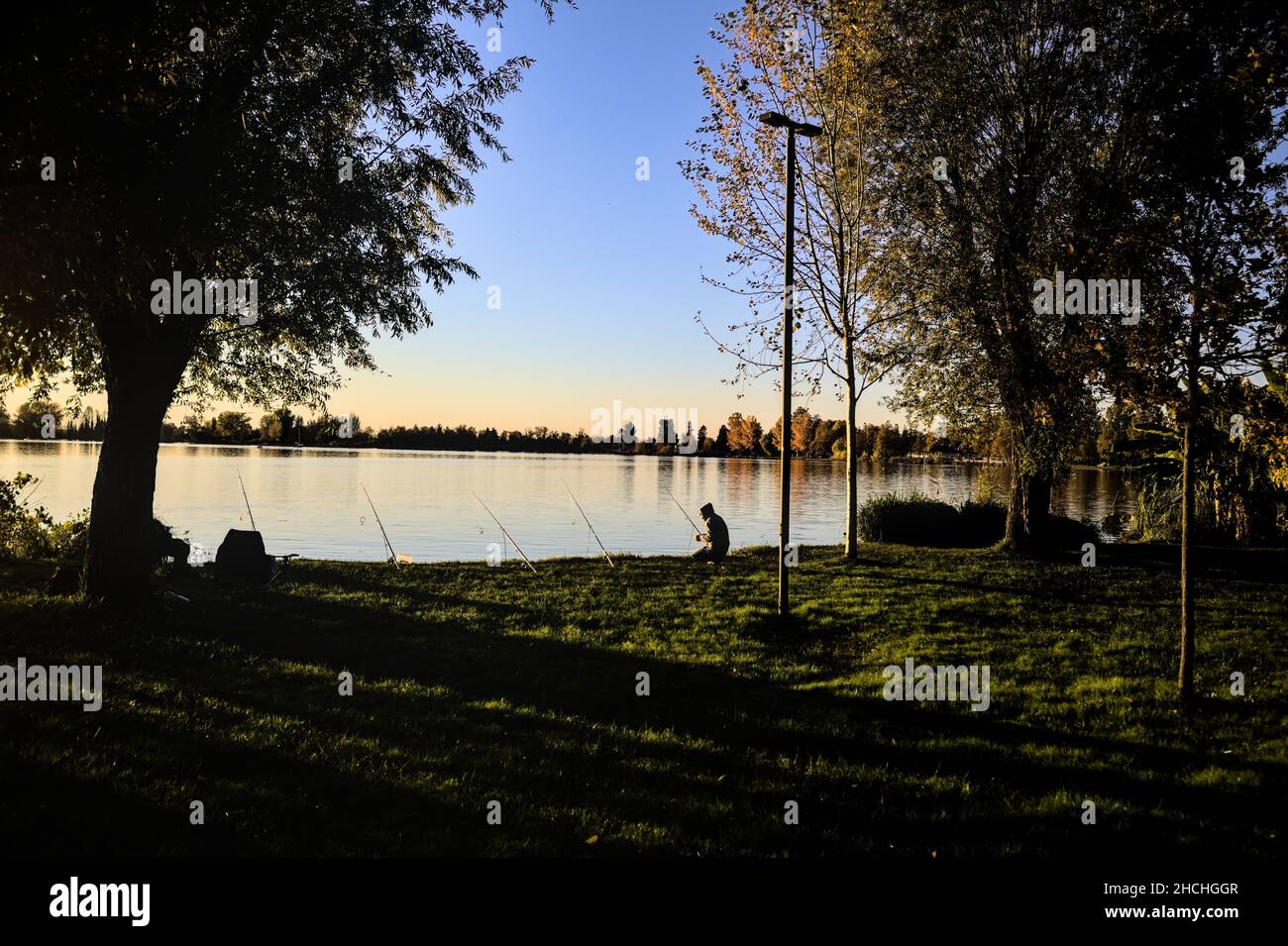 Fischer am Flussufer bei Dämmerung im Herbst Stockfoto