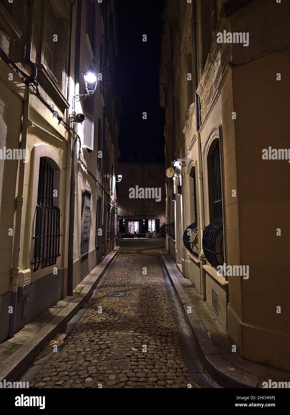 Schöne Nachtansicht der engen Gasse im historischen Zentrum von Avignon, Provence, Frankreich mit Straßenlaterne, Kopfsteinpflaster und historischen Gebäuden. Stockfoto